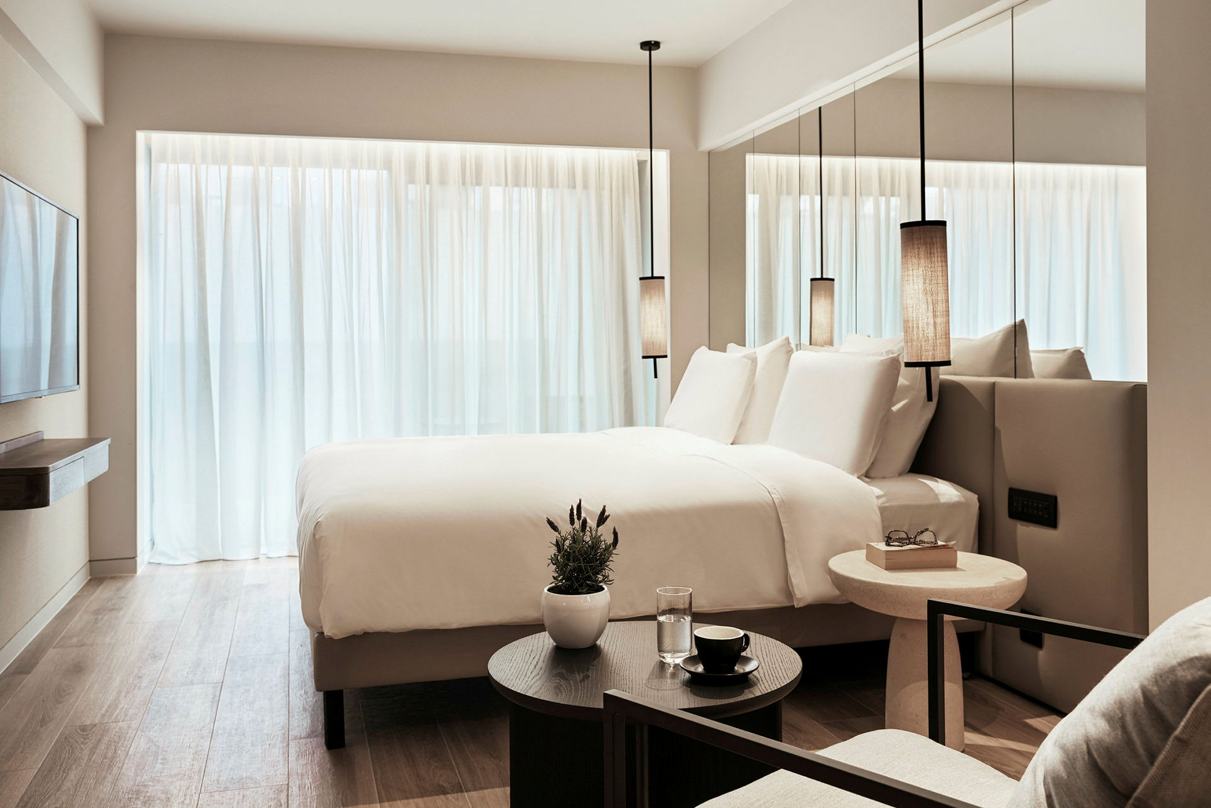 Moderni hotellihuone, jossa on iso sänky, valkoiset lakanat ja minimalistinen sisustus. (Tekoälyn luoma teksti)
