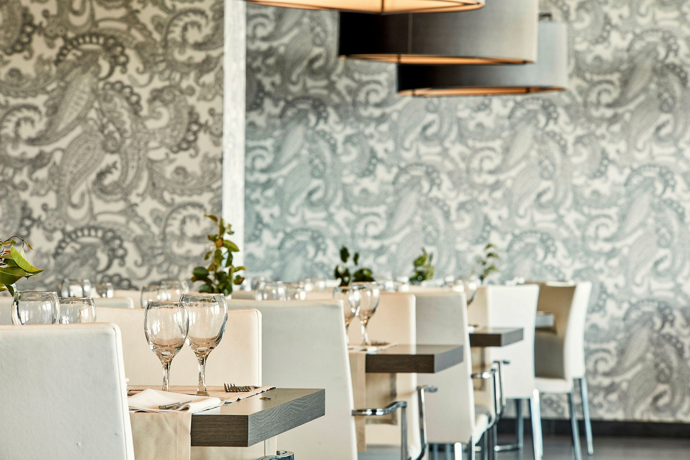Ravintola, jossa valkoisia tuoleja ja katettuja pöytiä. (Tekoälyn luoma teksti)
