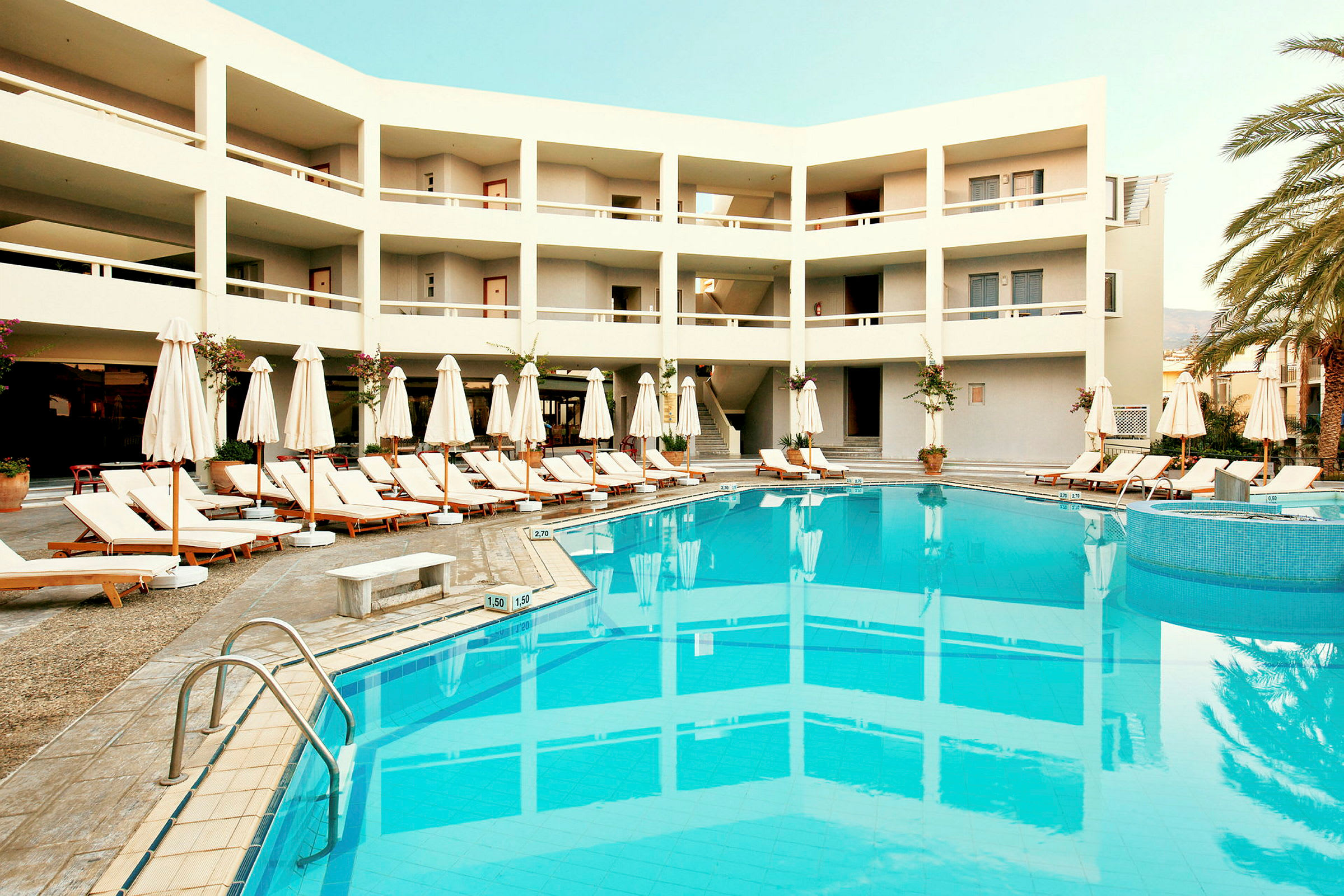Hotellirakennus, jossa uima-allas ja aurinkotuoleja. (Tekoälyn luoma teksti)