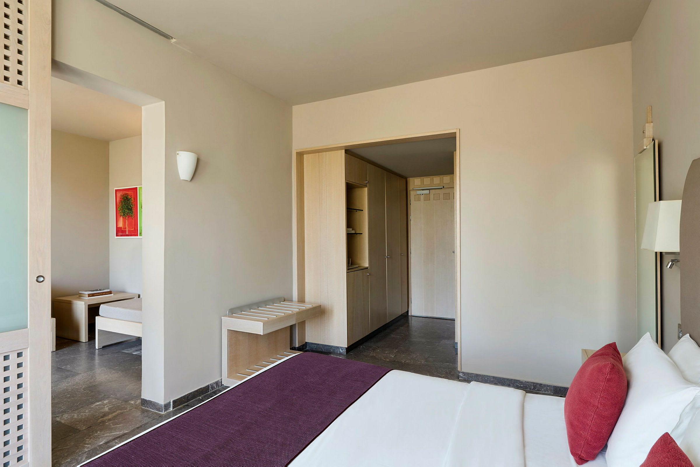 Hotellihuone, jossa on sänky, vaatekaappi ja istuinryhmä. (Tekoälyn luoma teksti)
