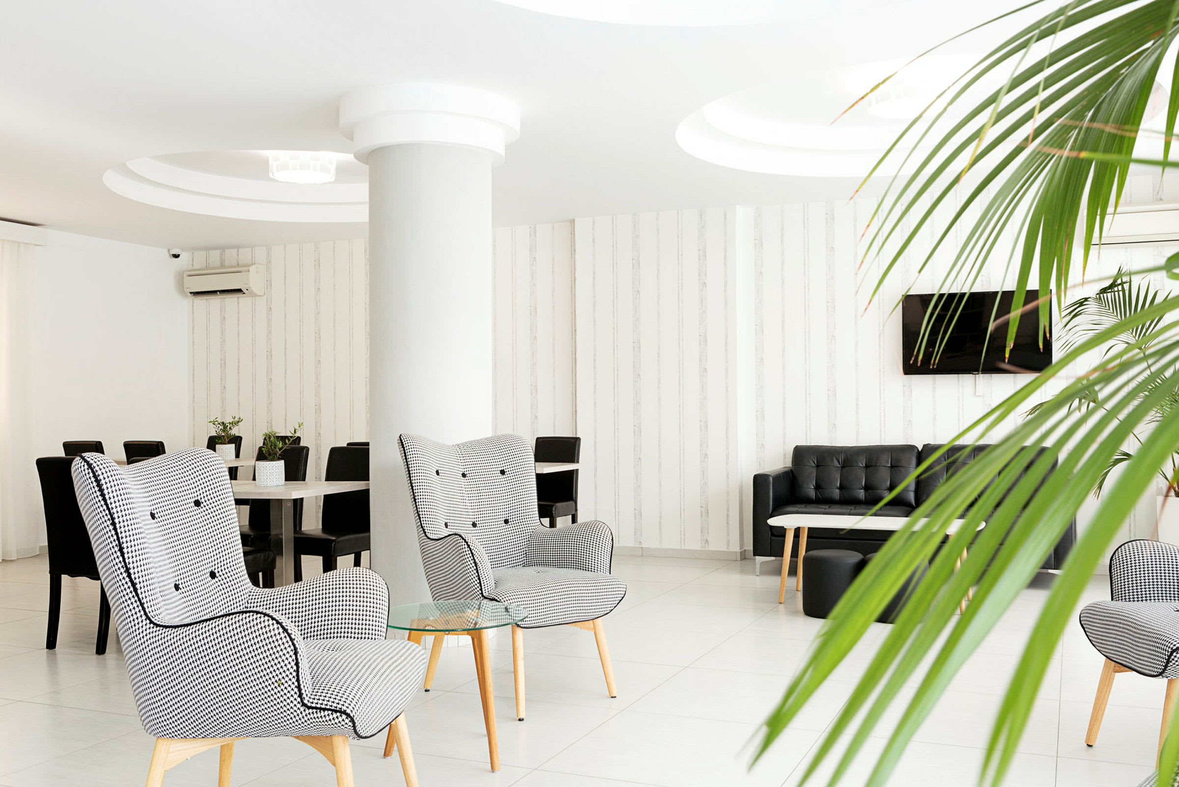 Nykyaikainen hotelliaula, jossa nojatuoleja, sohvia ja kasvikoristeita. (Tekoälyn luoma teksti)
