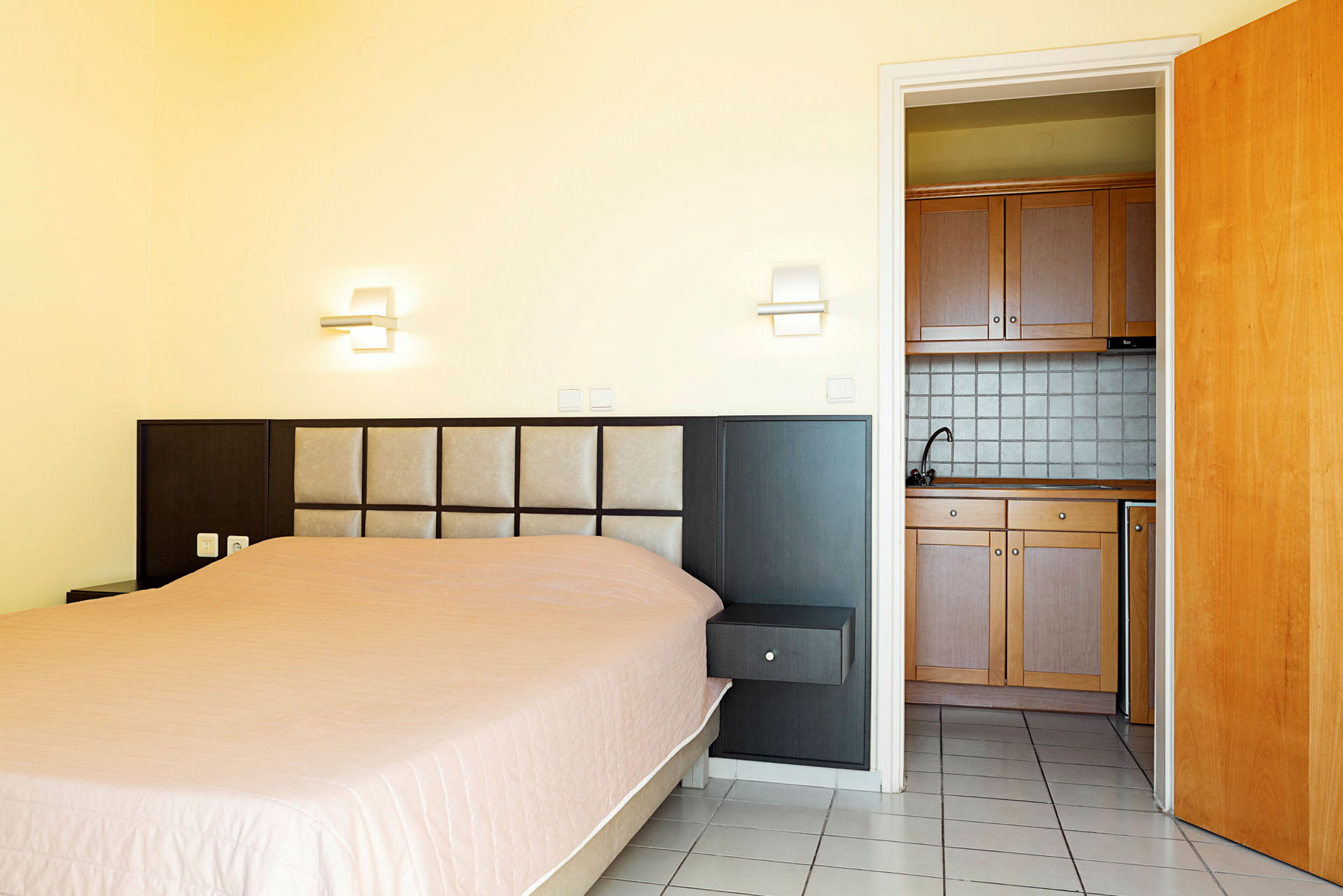 Hotellihuone, jossa on sänky ja pieni keittiö. (Tekoälyn luoma teksti)