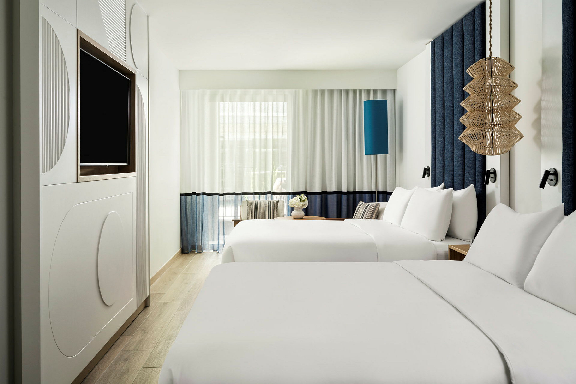 Hotellihuone, jossa kaksi parisänkyä ja moderni sisustus. (Tekoälyn luoma teksti)