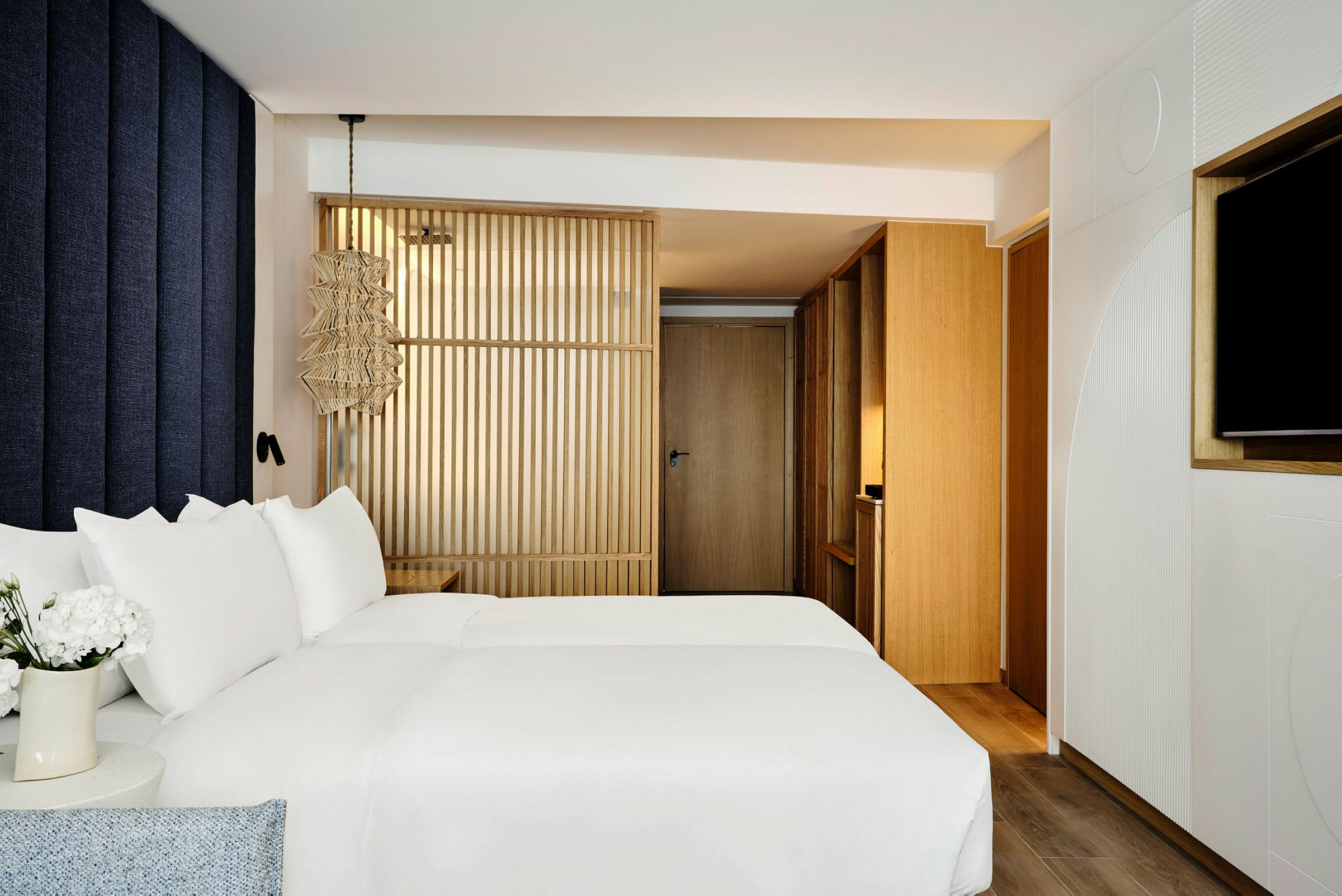 Kuva modernista hotellihuoneesta, jossa on valkoiset lakanat ja puukoristeluja. (Tekoälyn luoma teksti)
