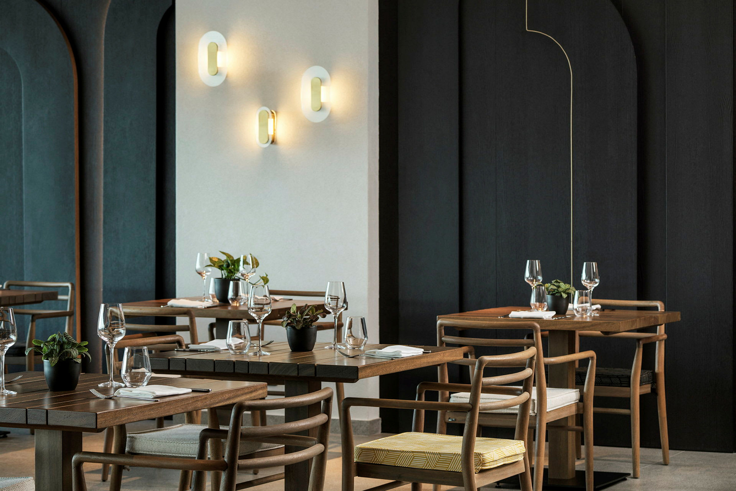 Tyylikäs ravintola, jossa on puupöytiä, tuoleja ja seinävaloja. (Tekoälyn luoma teksti)