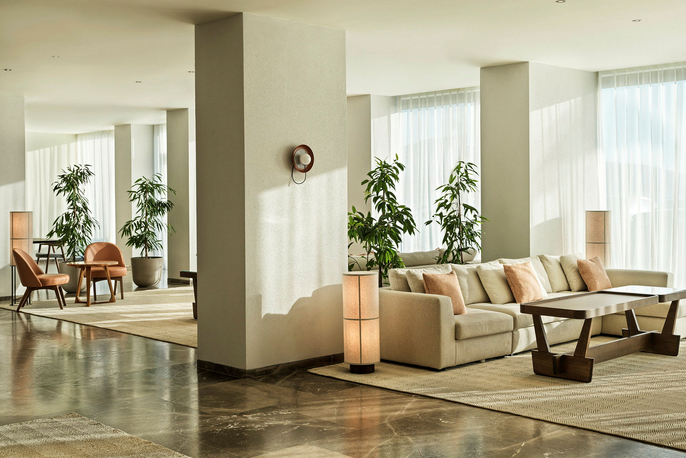 Moderni hotellihuone, jossa on sohvaryhmä ja vihreitä kasveja. (Tekoälyn luoma teksti)