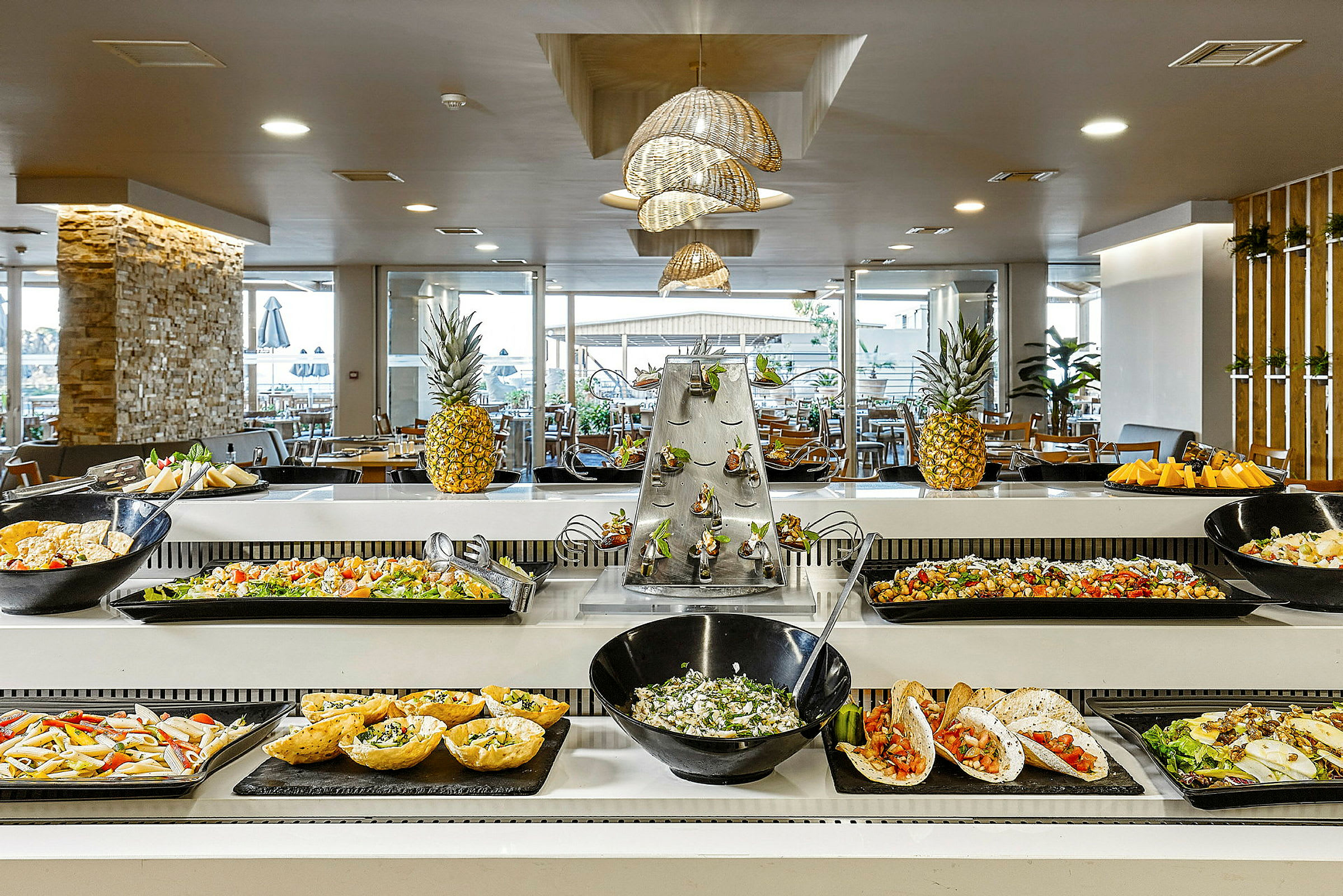 Buffet, jossa on erilaisia ruokia ja koristeellisia ananaksia pöydällä. (Tekoälyn luoma teksti)