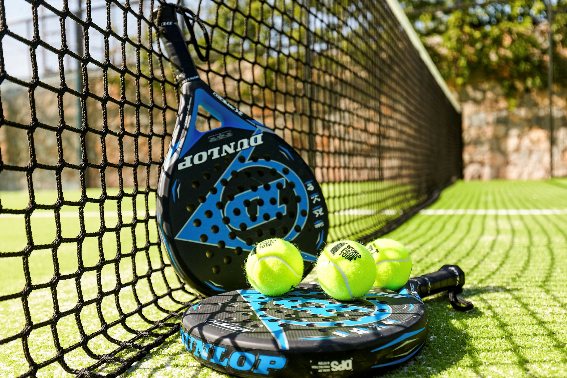 Padelmaila ja padelpalloja verkon vieressä padelkentällä. (Tekoälyn luoma teksti)