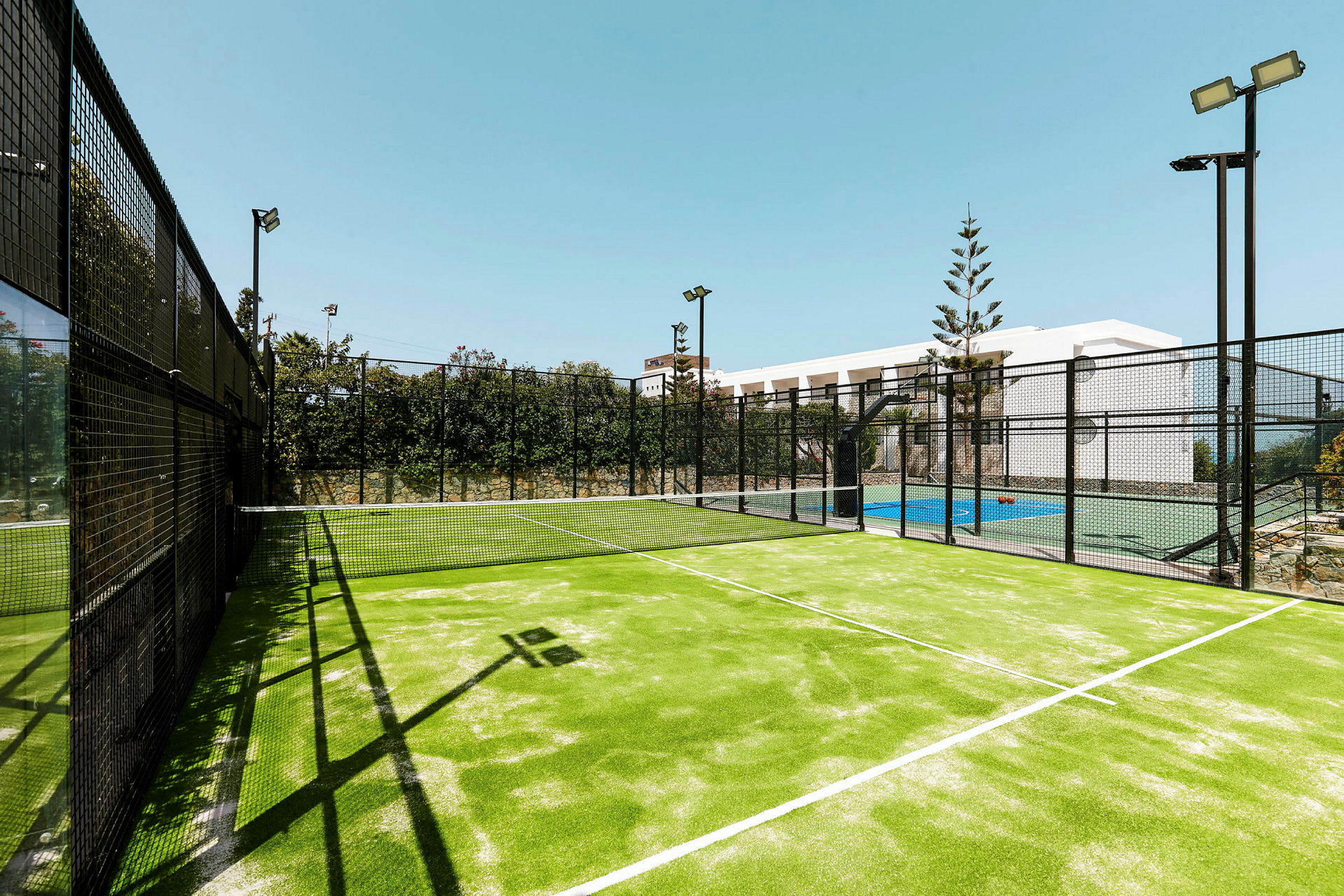 Ulkona sijaitseva valaistu padelkenttä, jonka keskellä on verkko. (Tekoälyn luoma teksti)