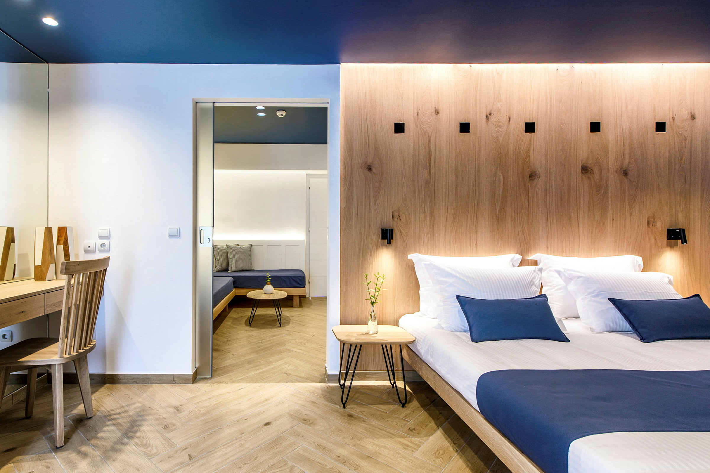 Modernisti sisustettu hotellihuone, jossa on parisänky ja oleskelualue. (Tekoälyn luoma teksti)