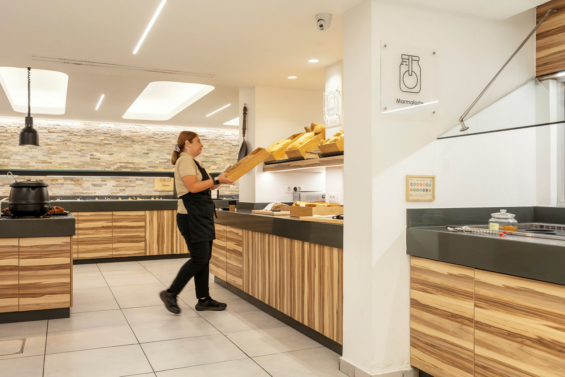 Henkilö järjestelee leipää valoisassa ja modernissa tarjoiluympäristössä. (Tekoälyn luoma teksti)