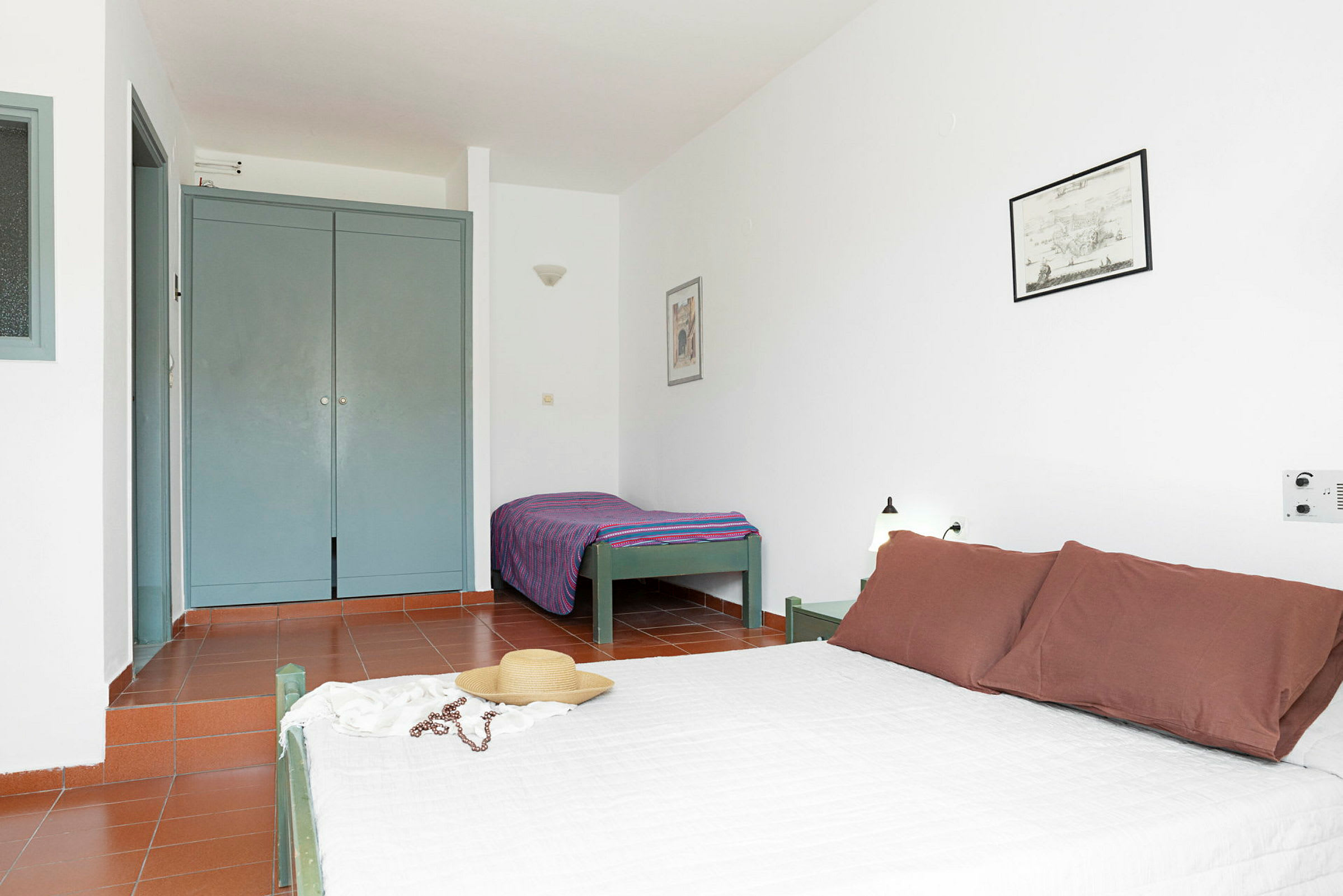 Hotellihuone, jossa on parivuode ja yhden hengen vuode, vaatekaappi ja minimalistinen sisustus. (Tekoälyn luoma teksti)