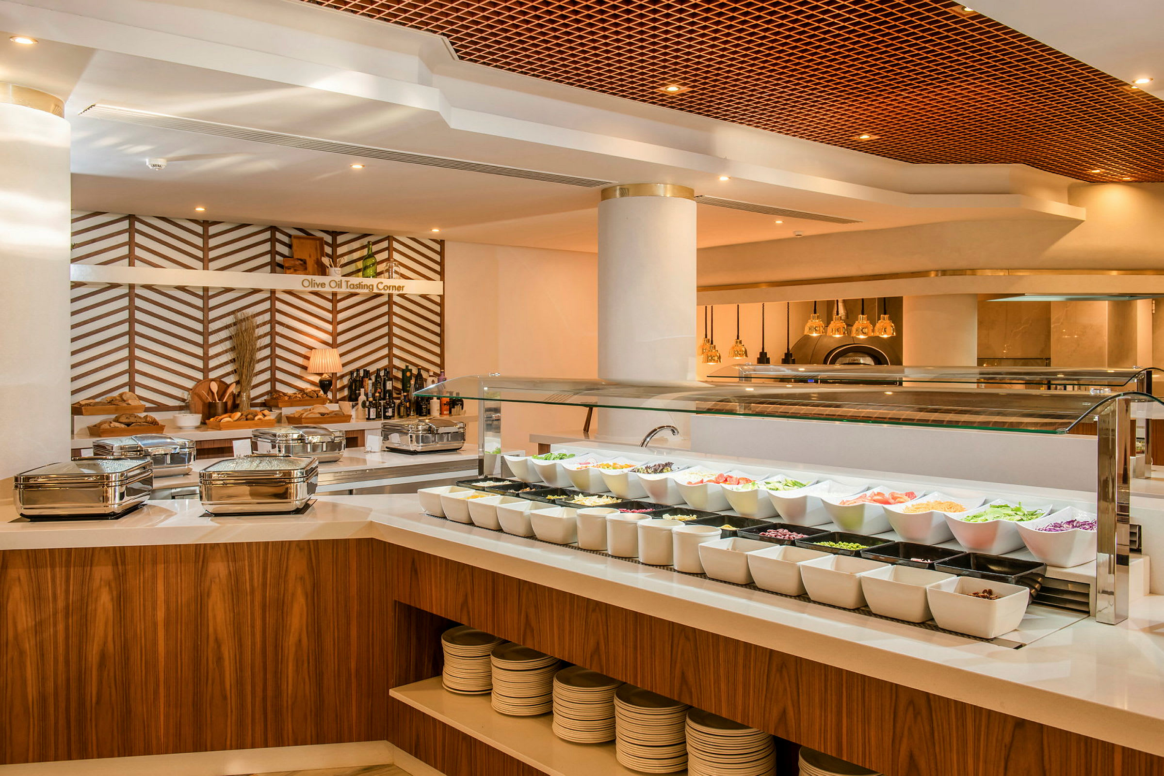 Buffet-alue, jossa salaattivalikoima ja oliiviöljyn maistelupaikka tyylikkäässä ravintolaympäristössä. (Tekoälyn luoma teksti)