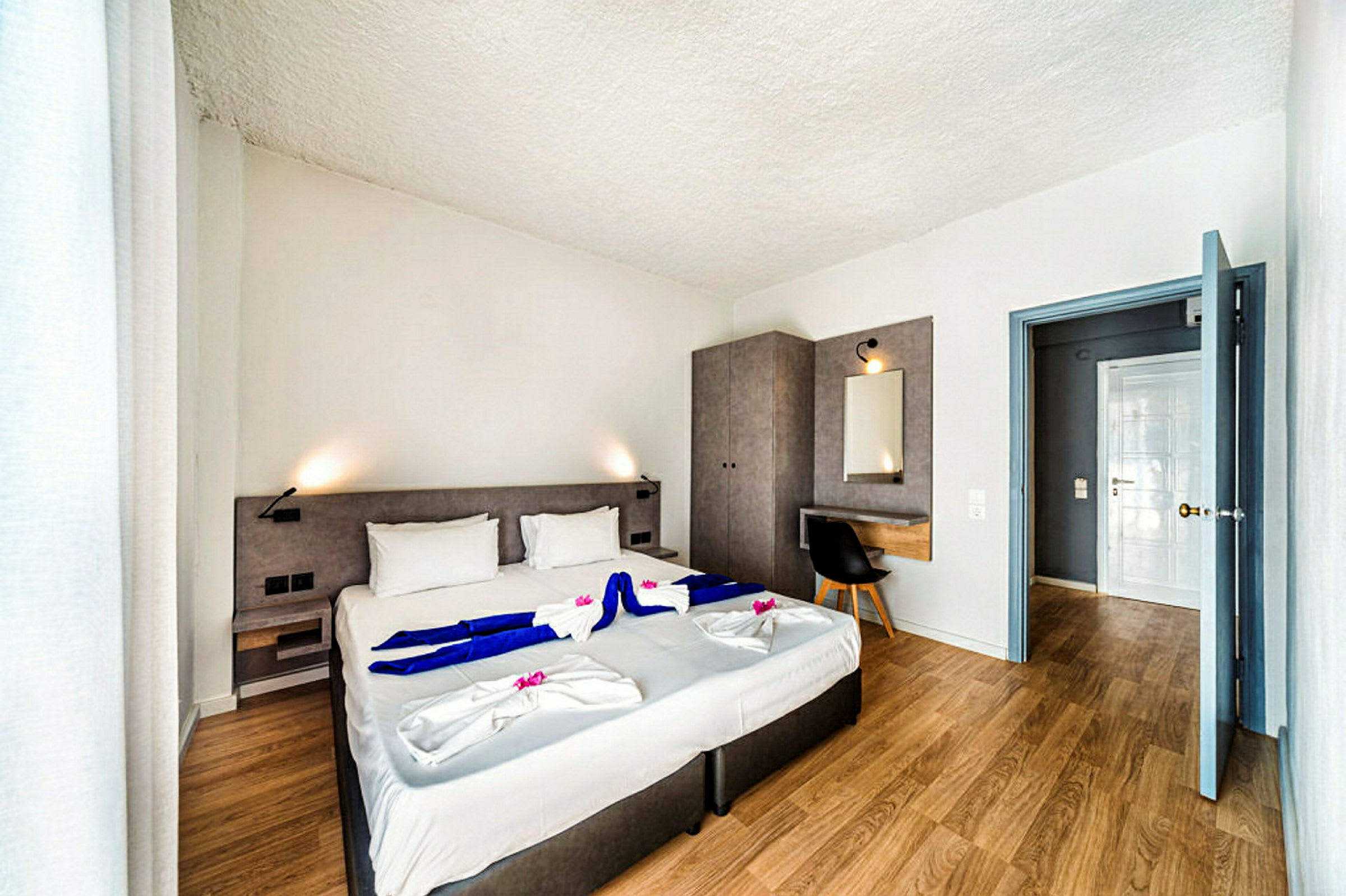 Moderni hotellihuone, jossa on parivuode, työpöytä ja vaatekaappi. (Tekoälyn luoma teksti)