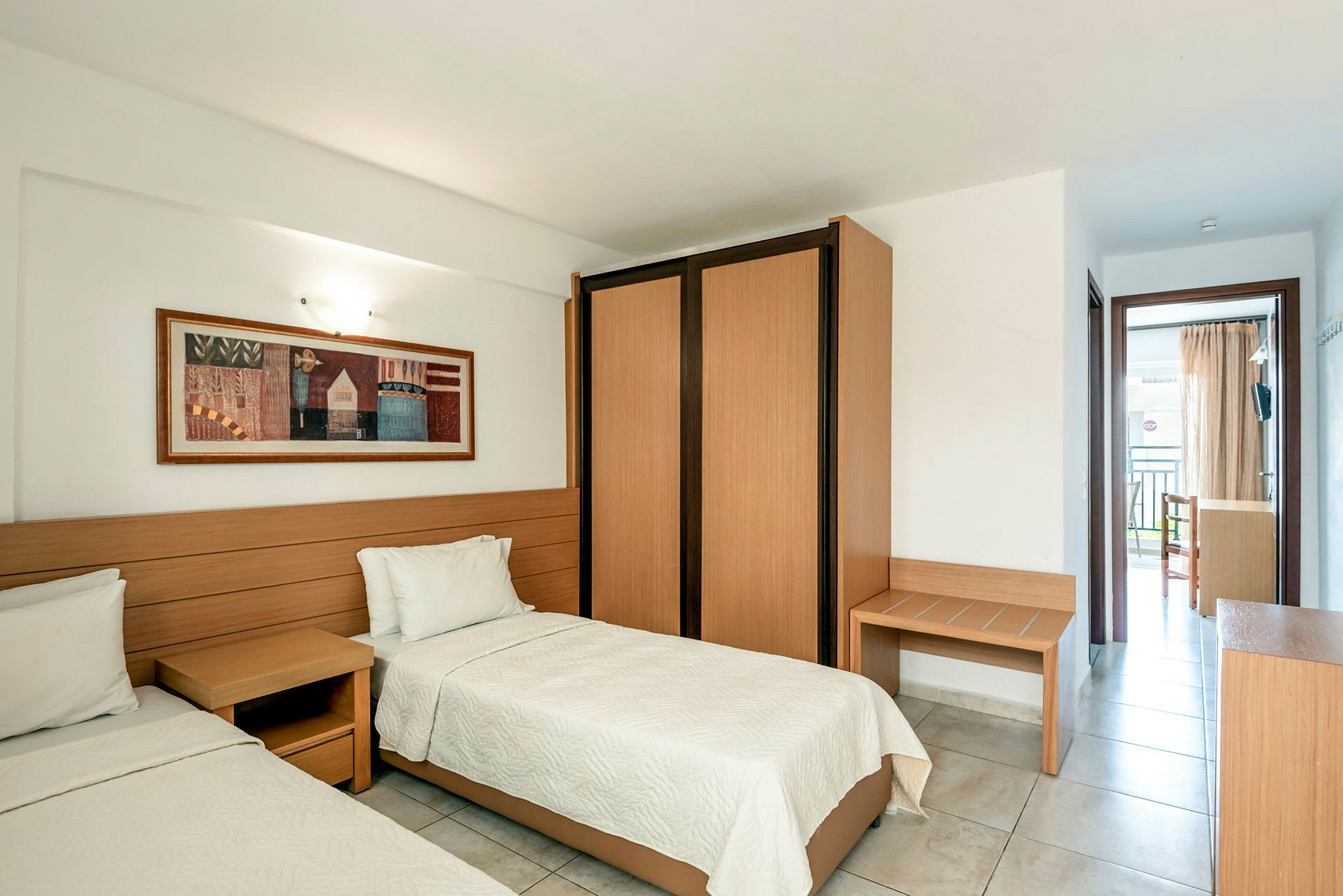 Hotellihuone, jossa on kaksi erillistä sänkyä, puinen seinäpaneeli ja vaatekaappi. (Tekoälyn luoma teksti)