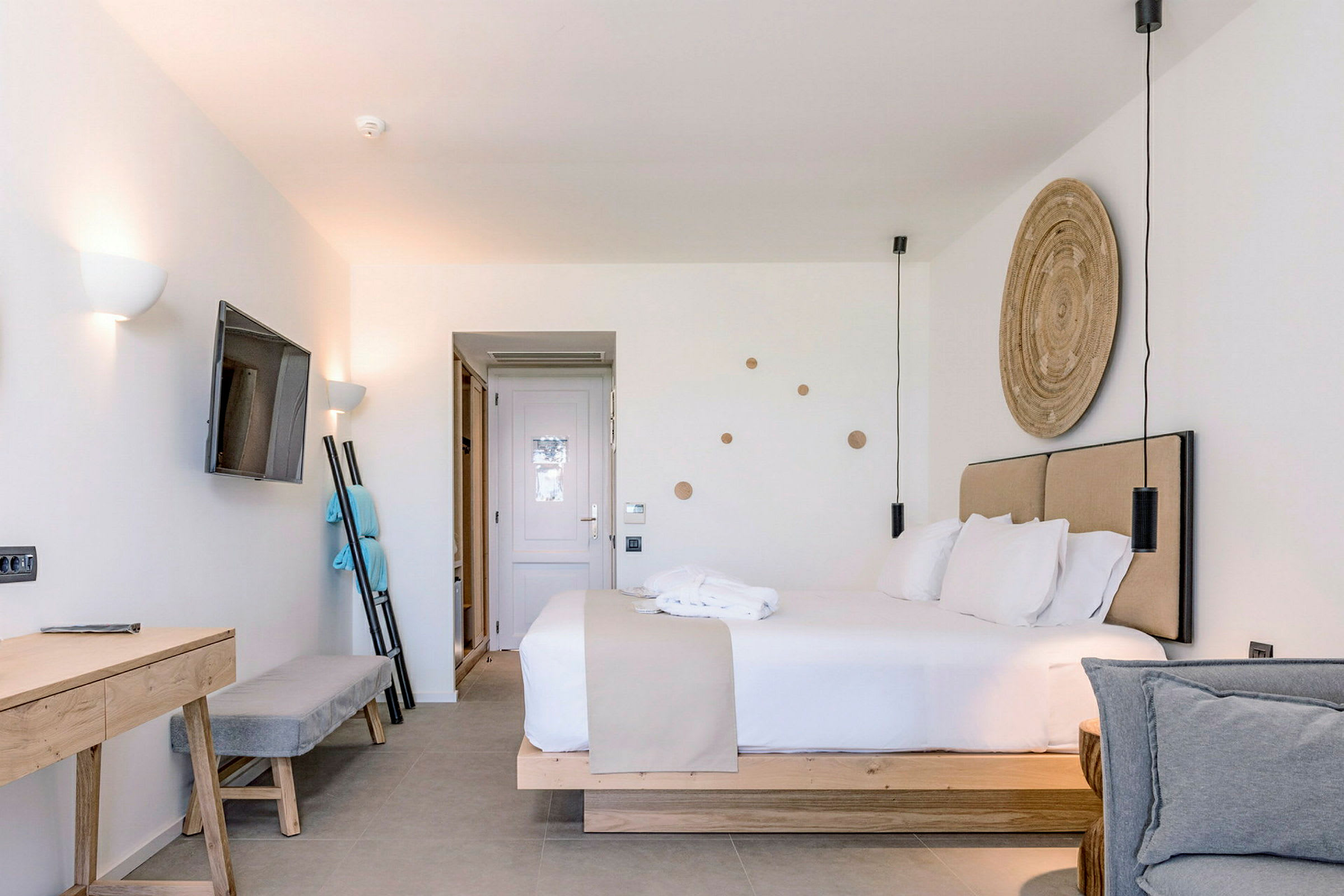 Nykyaikainen hotellihuone, jossa on parivuode, seinään kiinnitetty televisio ja kirjoituspöytä. (Tekoälyn luoma teksti)