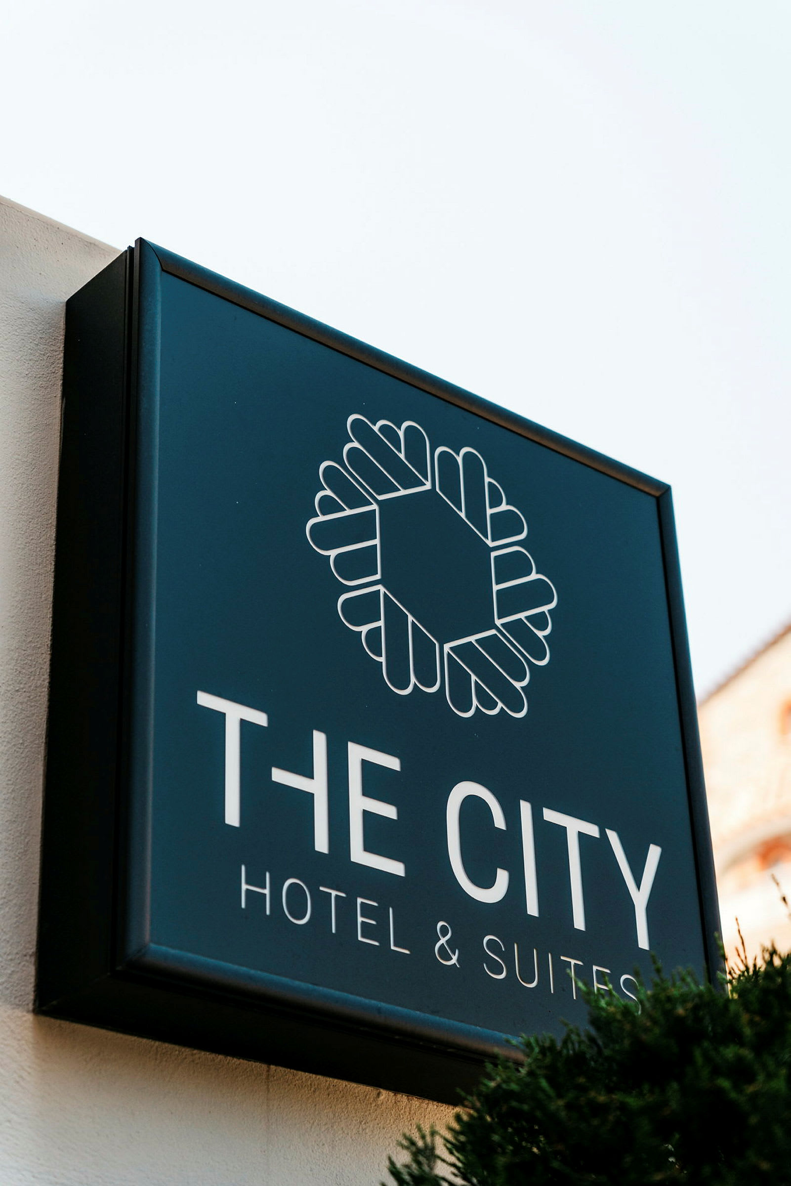 "The City Hotel & Suites" -kyltin valkoisella taustalla. (Tekoälyn luoma teksti)