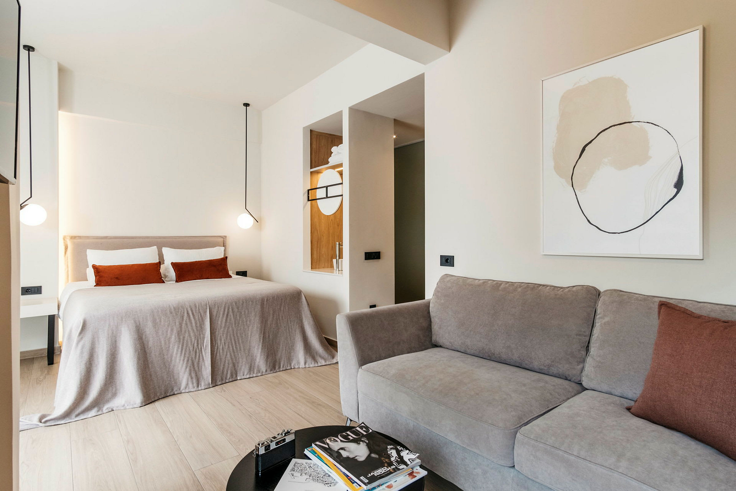 Moderni hotellihuone, jossa on suuri sänky, sohva ja minimalistinen sisustus. (Tekoälyn luoma teksti)