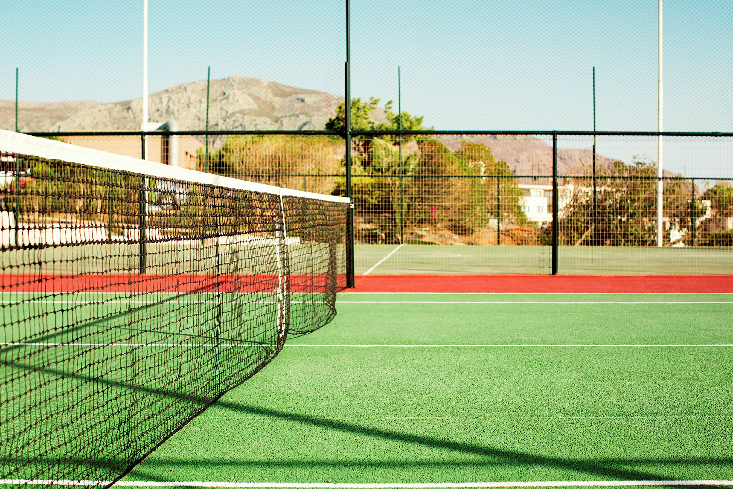 Tennisnurkka, jossa verkko ja aita. (Tekoälyn luoma teksti)