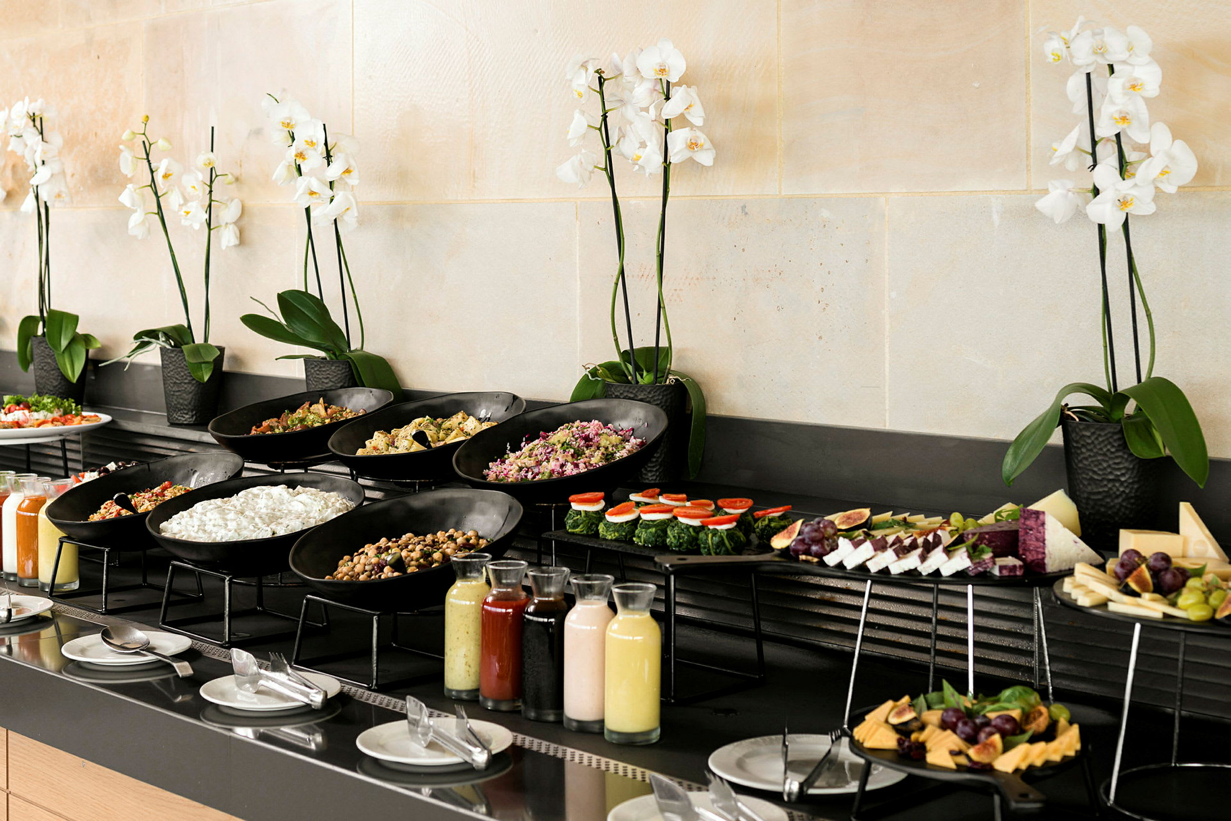 Buffet, jossa on erilaisia ruokia ja juomia, koristeltu valkoisilla orkideoilla. (Tekoälyn luoma teksti)