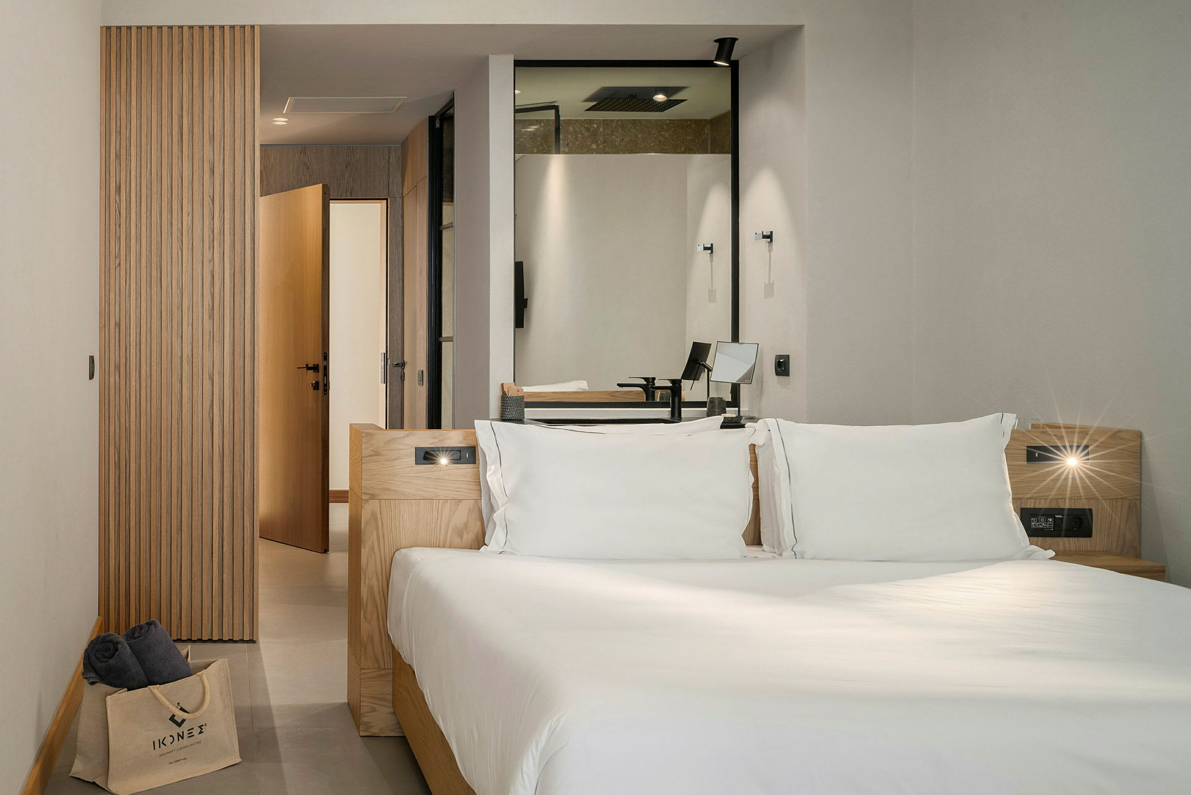 Moderni hotellihuone, jossa on parisänky, pääosin puuyksityiskohdilla sisustettu ja näkymä kylpyhuoneeseen. (Tekoälyn luoma teksti)