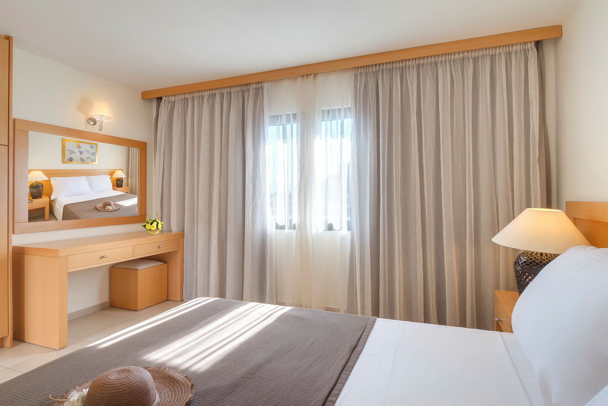 Hotellihuone, jossa on sänky, peili ja verhot ikkunassa. (Tekoälyn luoma teksti)