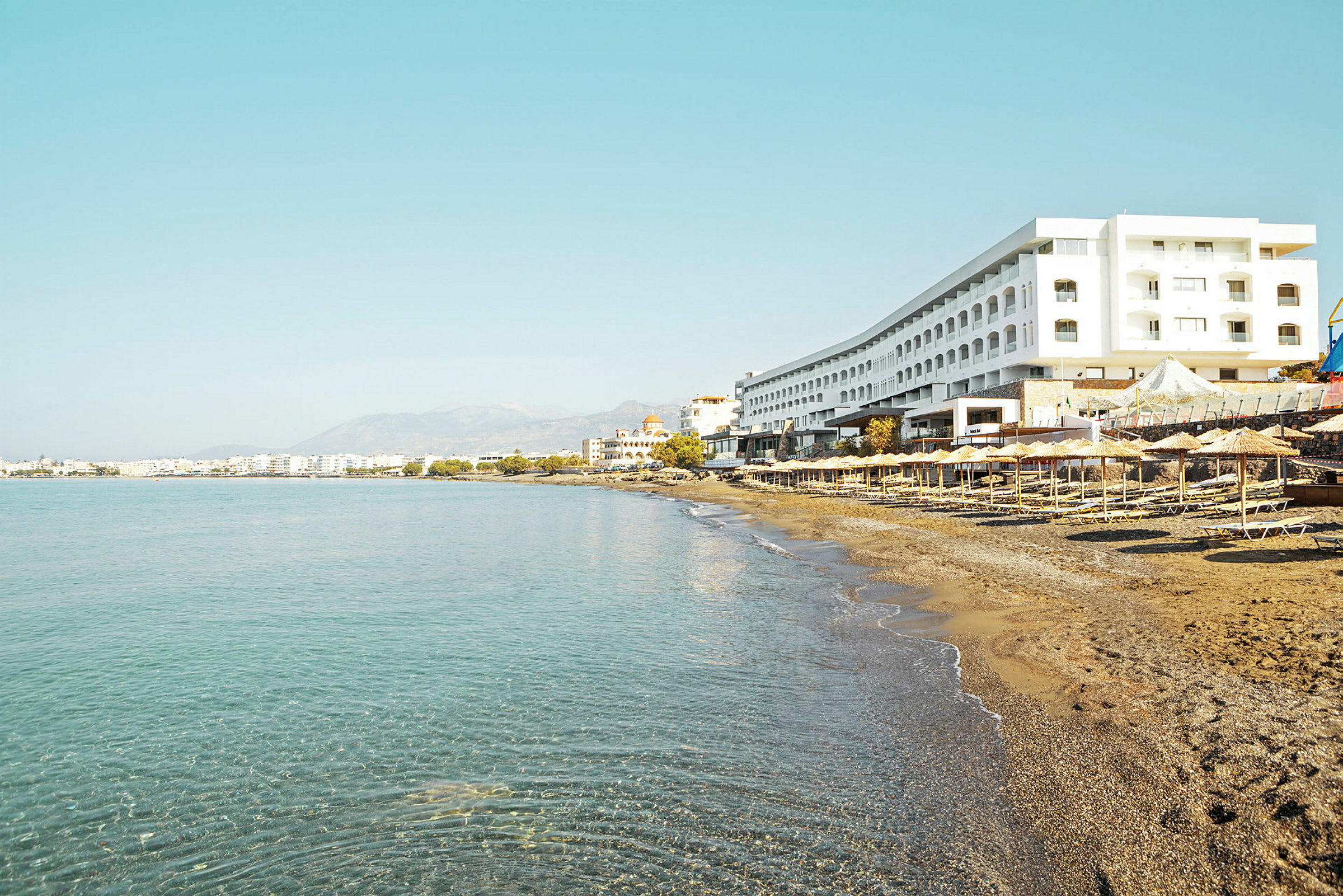Ranta aurinkotuoleilla ja varjoilla suuren hotellin juurella. (Tekoälyn luoma teksti)