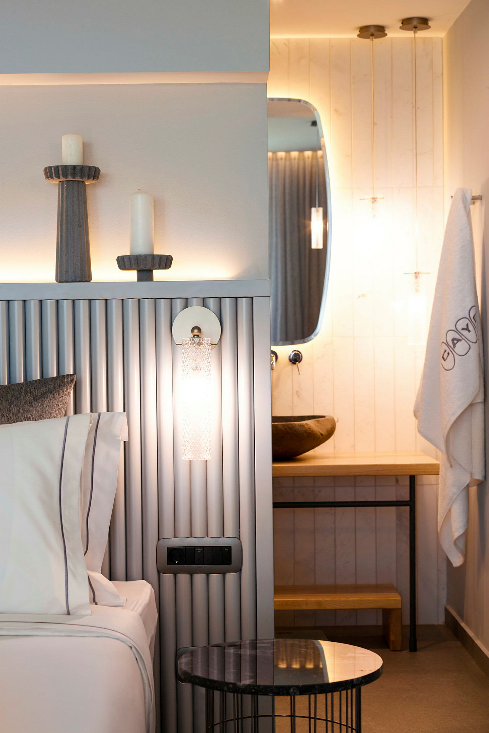 Moderni hotellihuone, jossa on sänky, koristeellinen pöytä ja kylpyhuone, jossa on peili. (Tekoälyn luoma teksti)