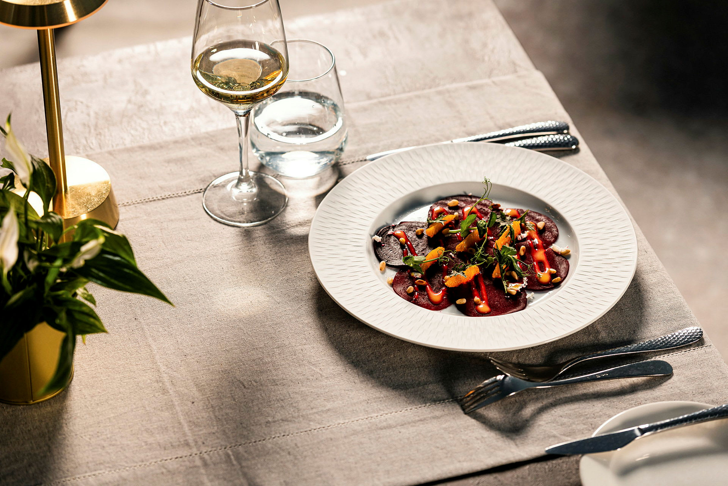 Lautasella gourmet-alkuruoka, jossa punajuuria ja lisukkeita katetulla pöydällä. (Tekoälyn luoma teksti)