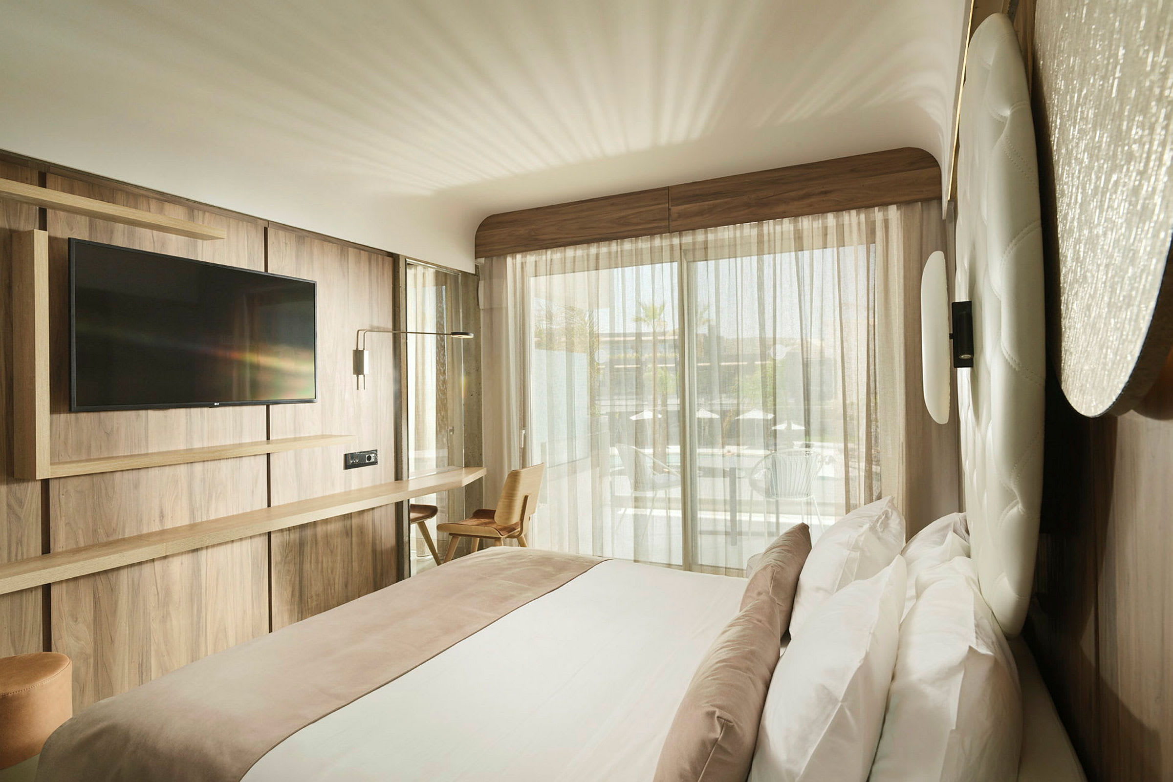 Moderni hotellihuone, jossa parivuode, seinään kiinnitetty televisio ja suuri ikkuna parvekkeelle. (Tekoälyn luoma teksti)