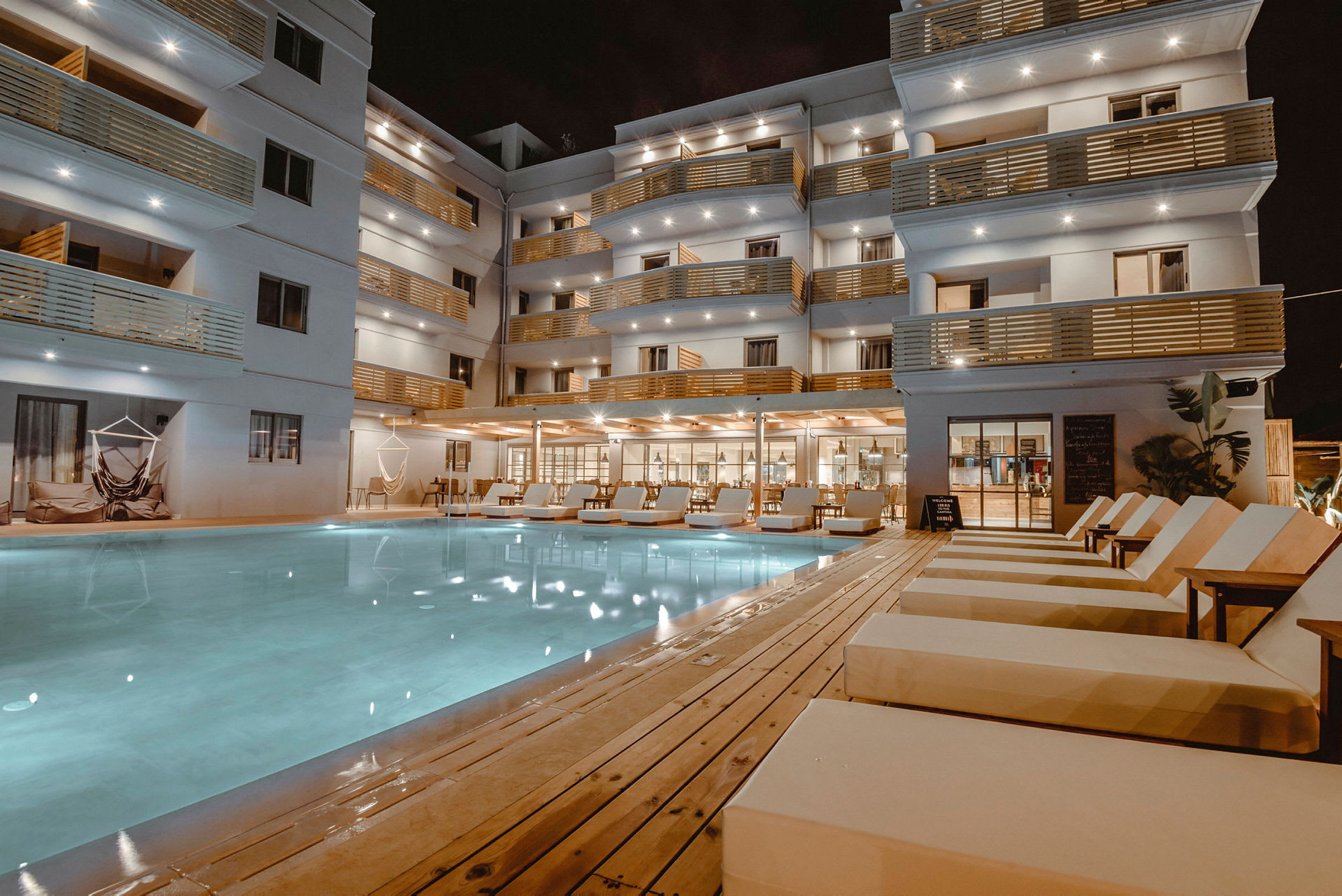 Hotellirakennus parvekkeineen ja ulkouima-allas aurinkotuoleilla. (Tekoälyn luoma teksti)