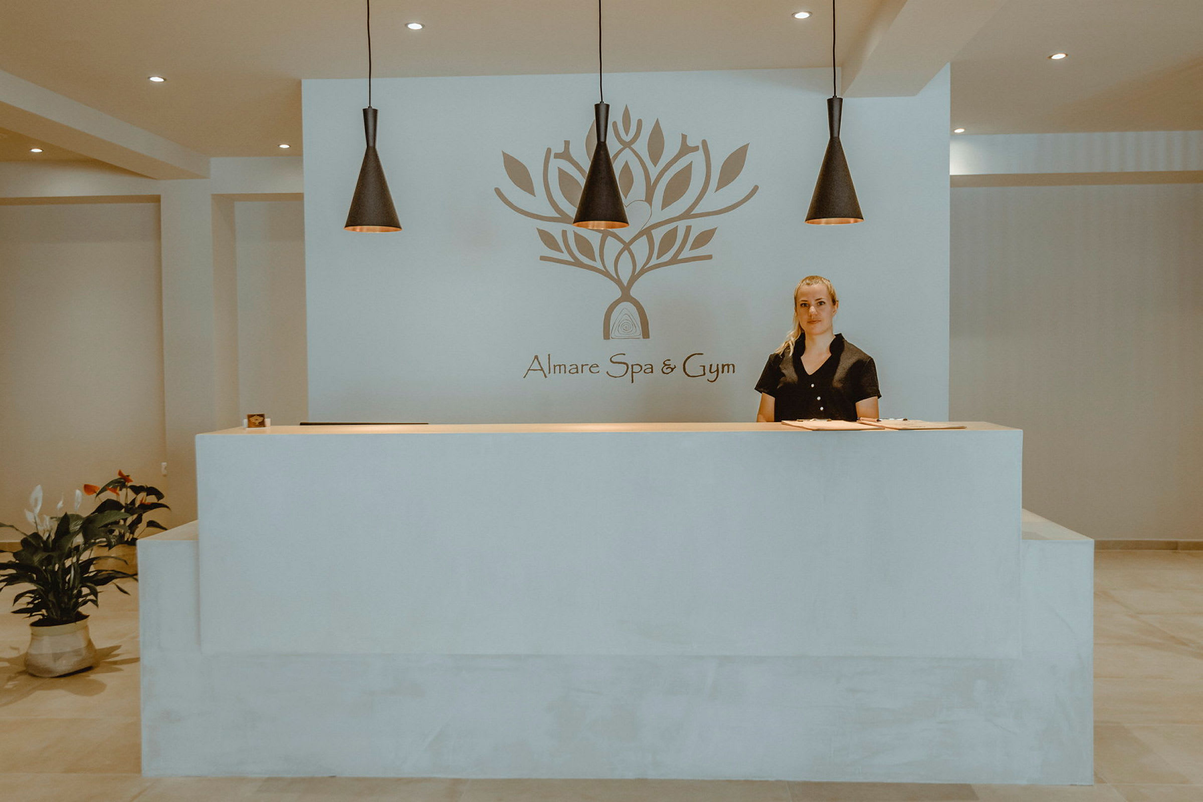 Almare Spa ja Gymin vastaanotto, seinällä logo ja yläpuolella koristeellinen valaistus. (Tekoälyn luoma teksti)
