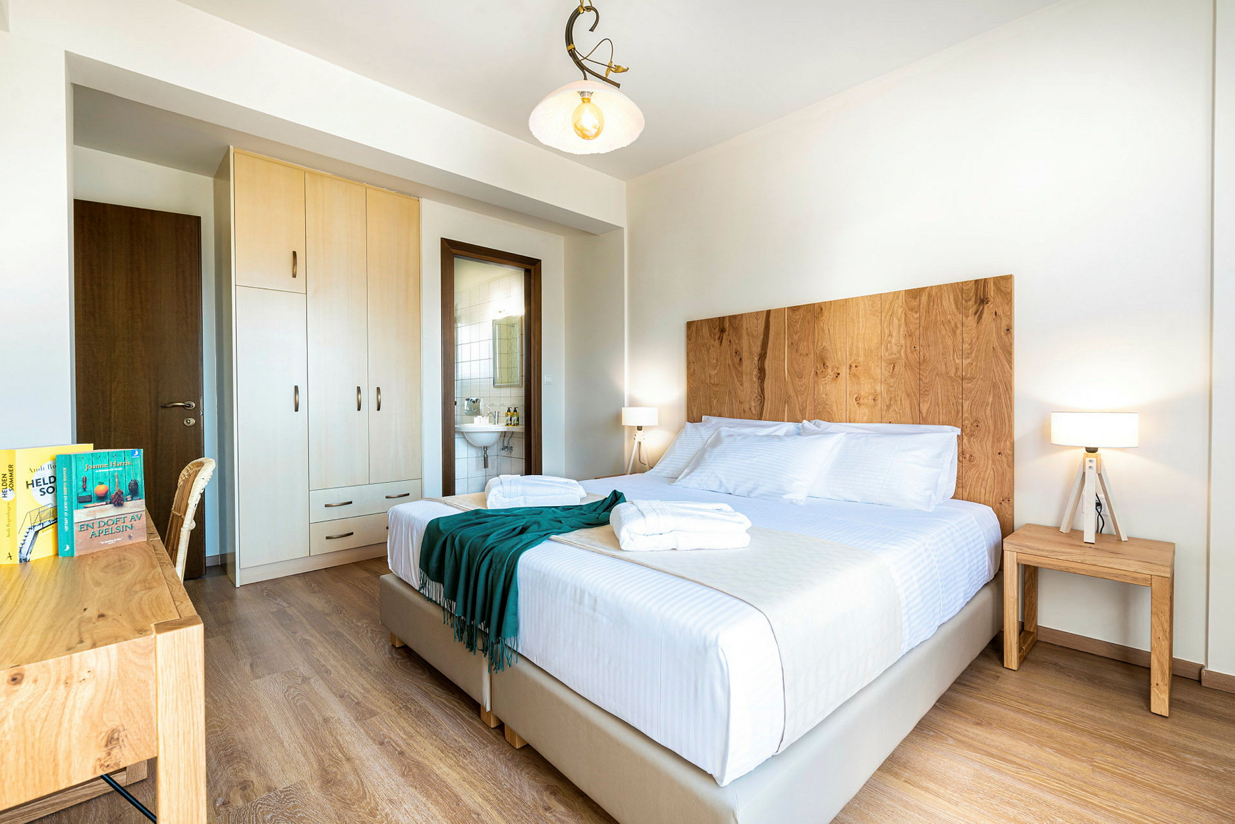 Valkoinen hotellihuone parivuoteella, puukoristeilla ja siisti. (Tekoälyn luoma teksti)
