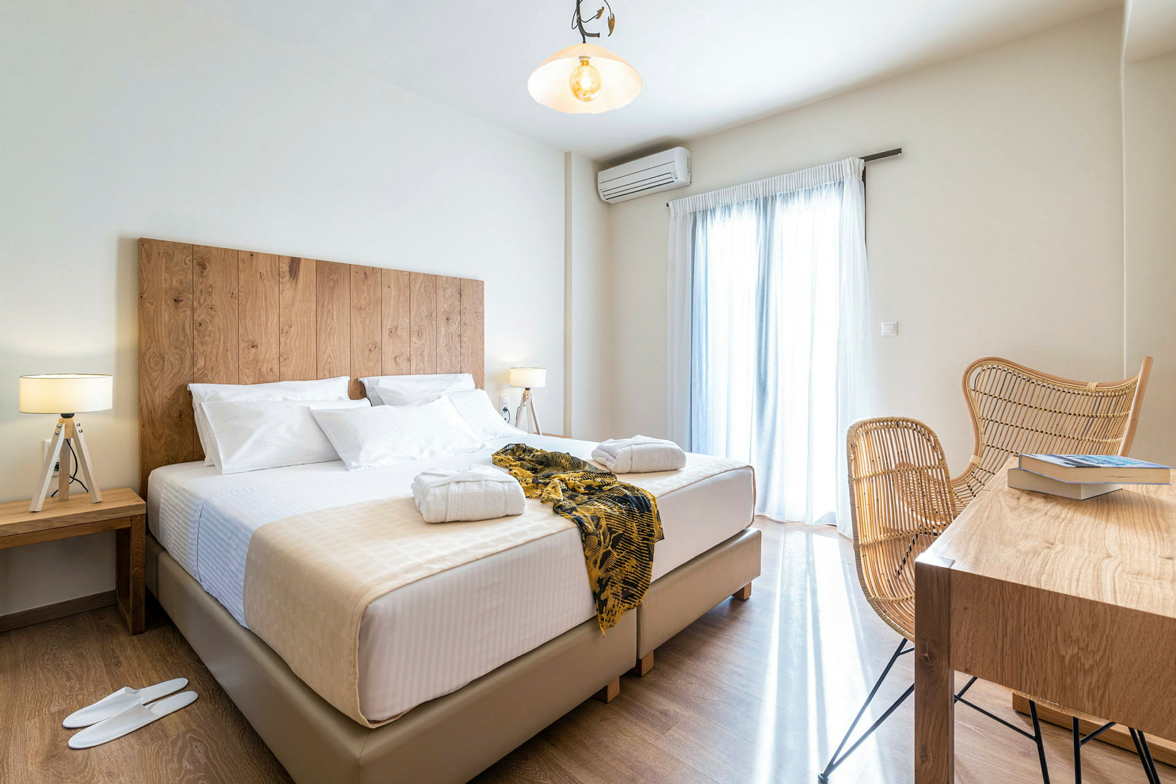 Hotellihuone, jossa on suuri sänky, yöpöytiä lampuilla sekä istuinryhmä ja pöytä kirjojen kanssa. (Tekoälyn luoma teksti)
