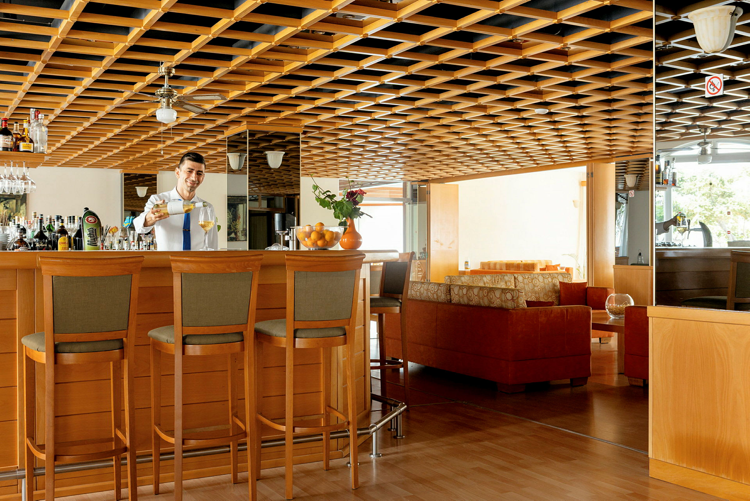 Modernisti sisustettu hotellibaari, jossa on puuyksityiskohtia ja istuinryhmiä. (Tekoälyn luoma teksti)