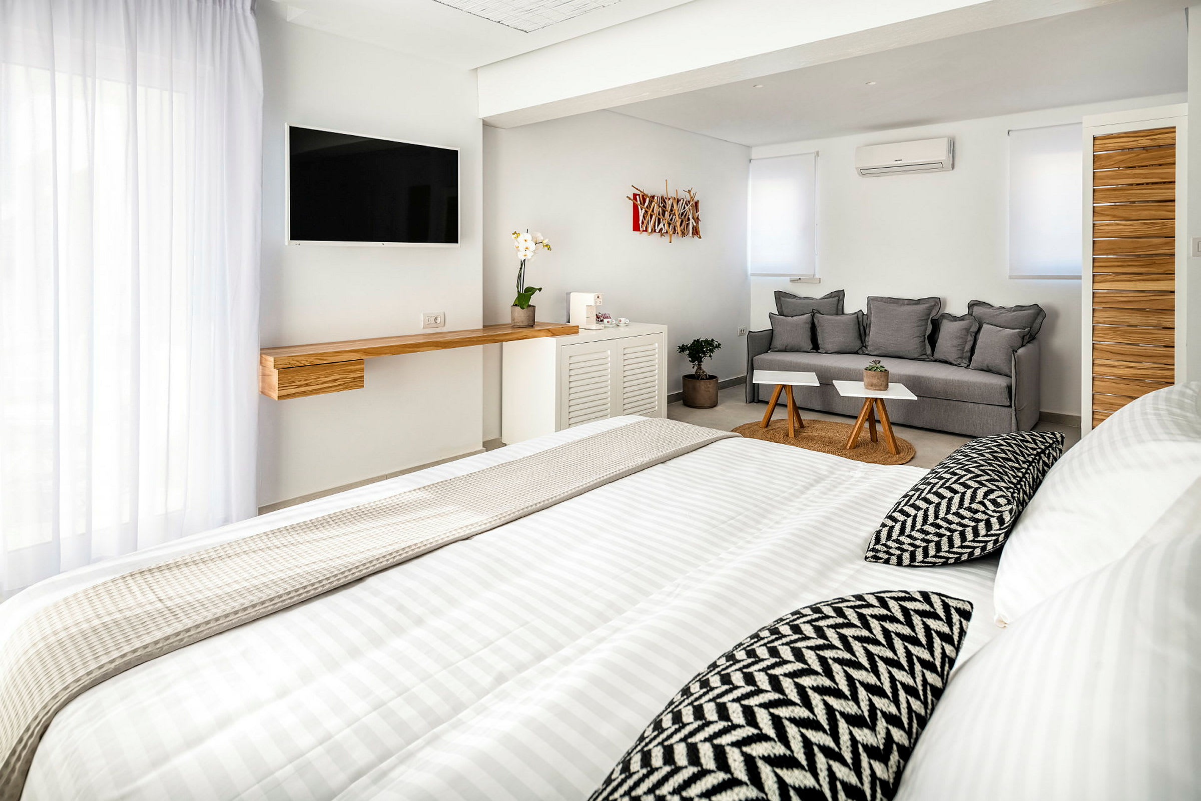 Valoisa, nykyaikainen hotellihuone, jossa on sänky, sohva ja televisio. (Tekoälyn luoma teksti)