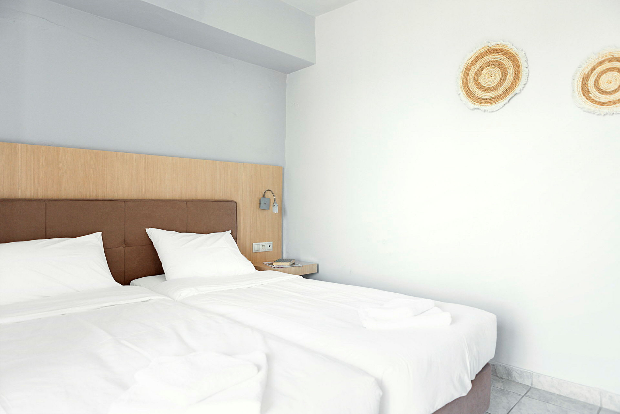 Hotellihuone, jossa kaksi erillistä vuodetta ja koristeita seinällä. (Tekoälyn luoma teksti)