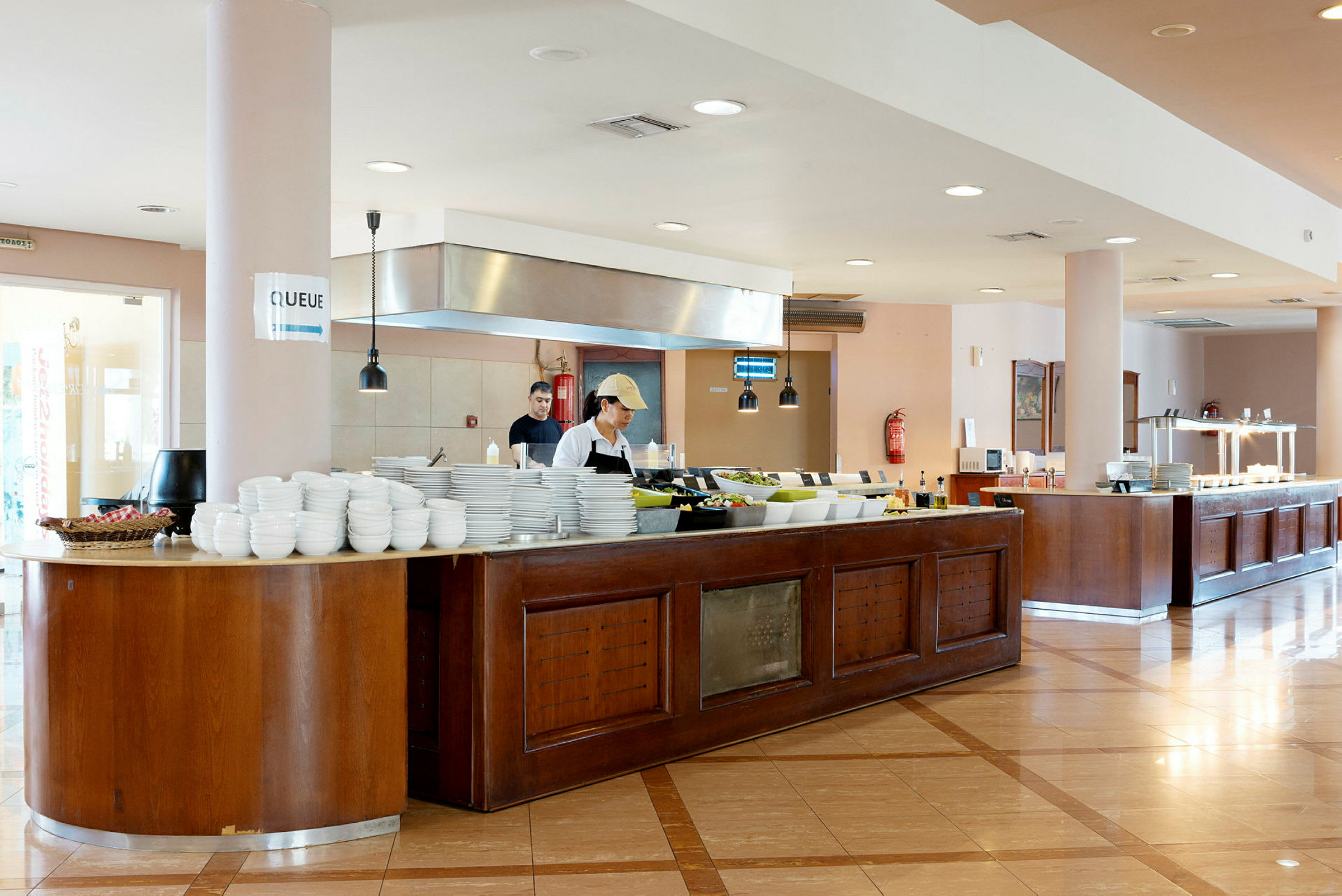 Buffet-ravintolan sisätila, jossa ruokatarjoilu, pöytiä, kattiloita ja lautasia näkyvissä. (Tekoälyn luoma teksti)