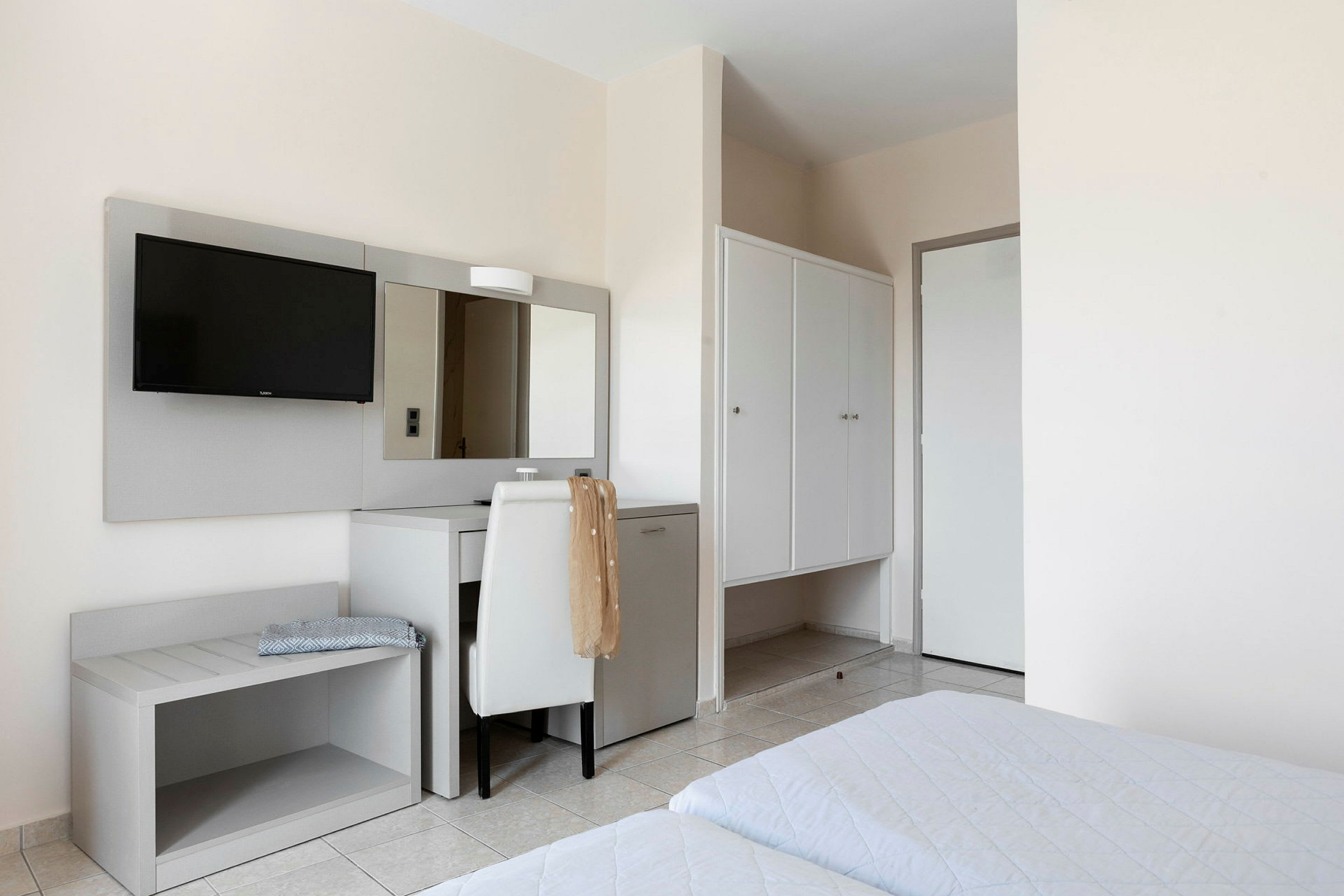 Hotellihuone, jossa sängyt, kirjoituspöytä, peili ja vaatekaappi. (Tekoälyn luoma teksti)