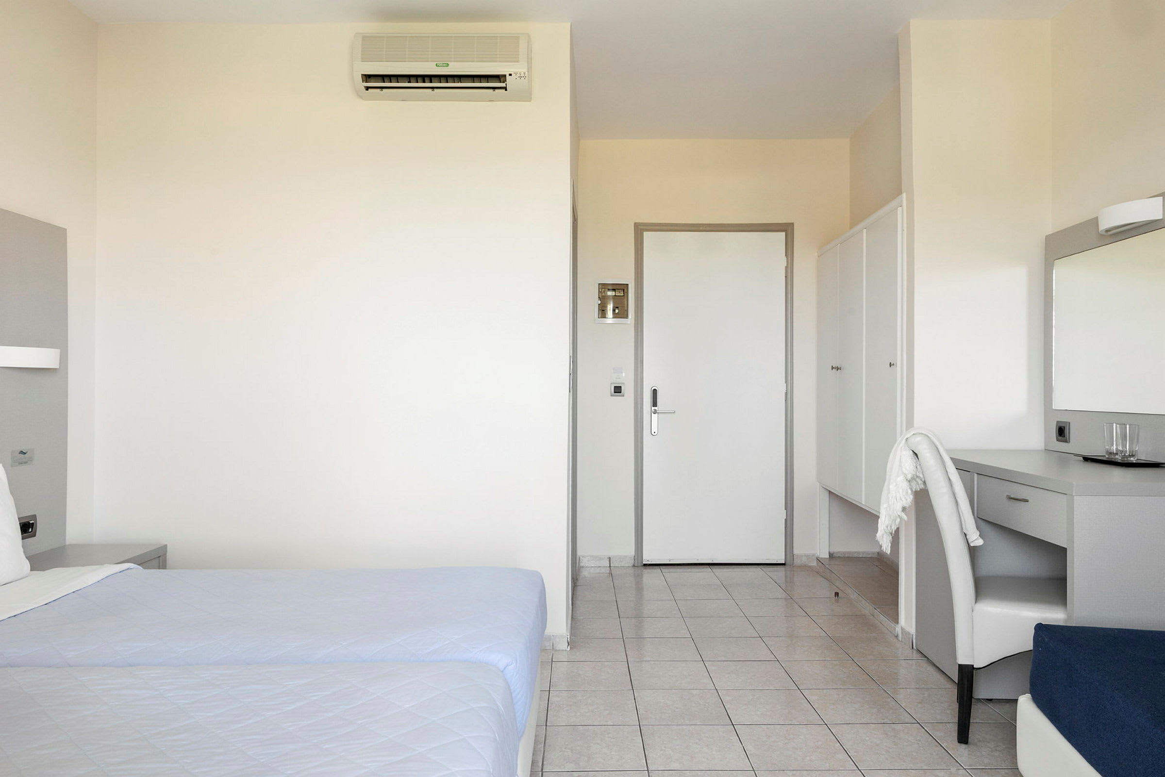 Hotellihuone, jossa on parivuoteet, työpöytä ja vaatekaapit. (Tekoälyn luoma teksti)