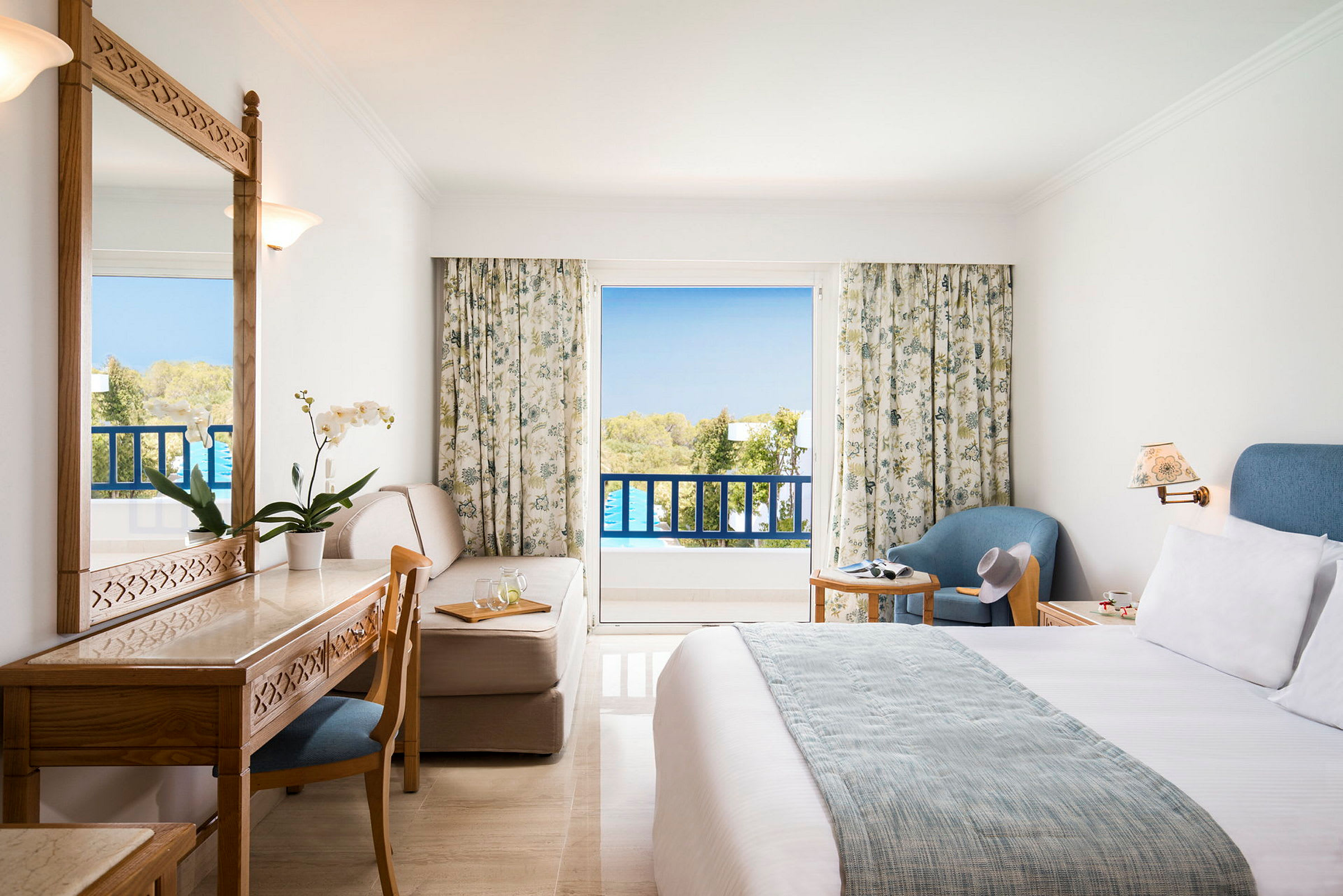 Hotellihuone, jossa parveke ja huonekalut, kuten sänky, kirjoituspöytä, tuoli ja nojatuoli. (Tekoälyn luoma teksti)