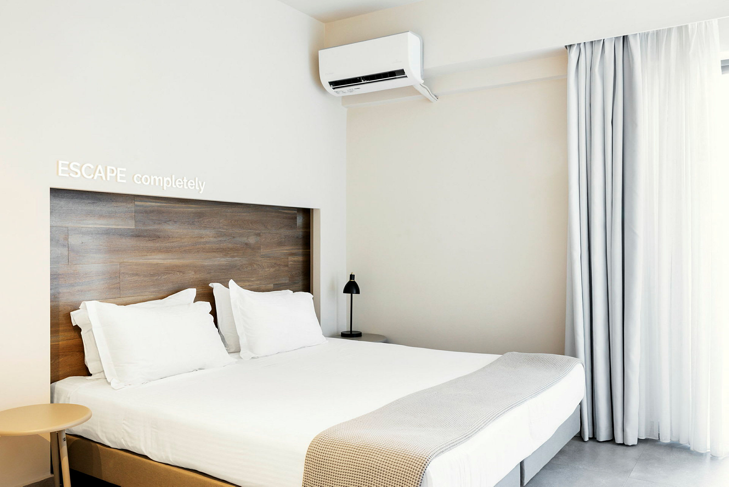 Nykyaikainen hotellihuone, jossa on parisänky, vaalea sisustus ja ilmastointi. (Tekoälyn luoma teksti)