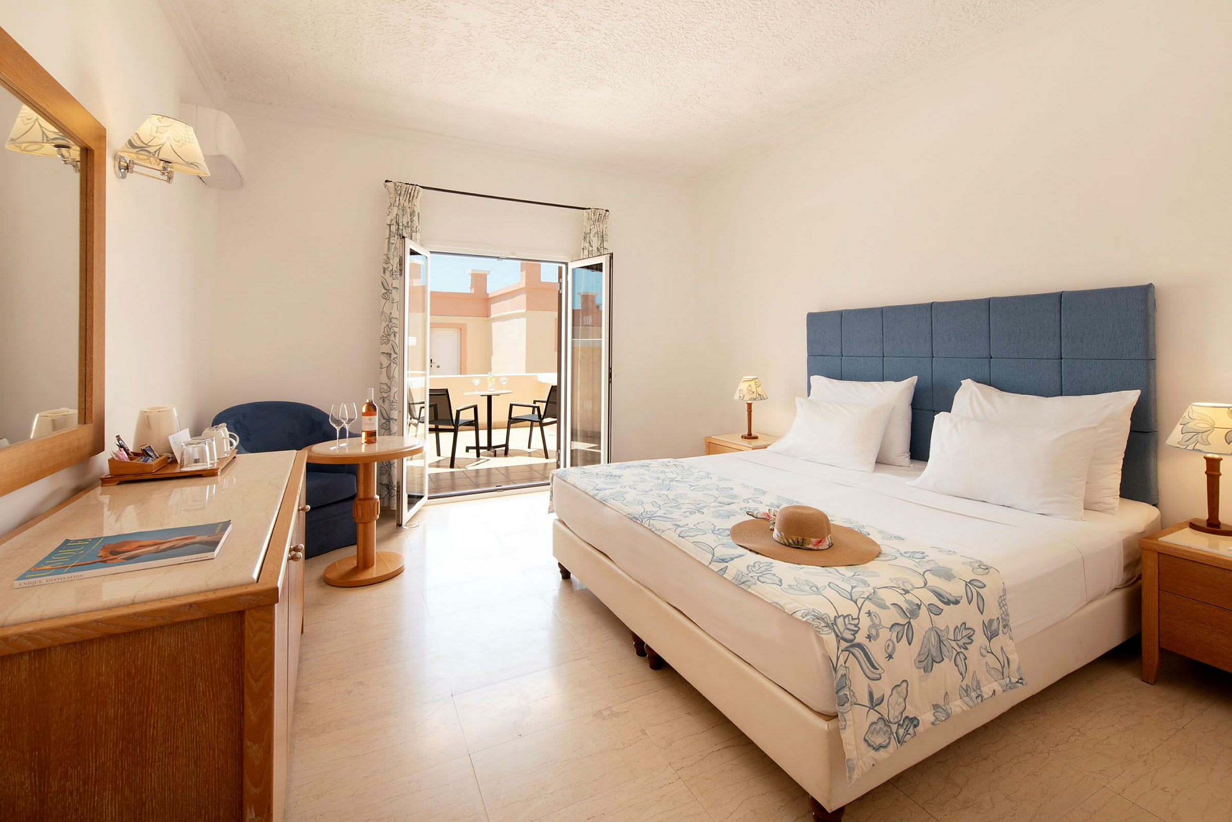 Hotellihuone, jossa parivuode, istuinryhmä, ikkuna ja sisustettu terassi. (Tekoälyn luoma teksti)