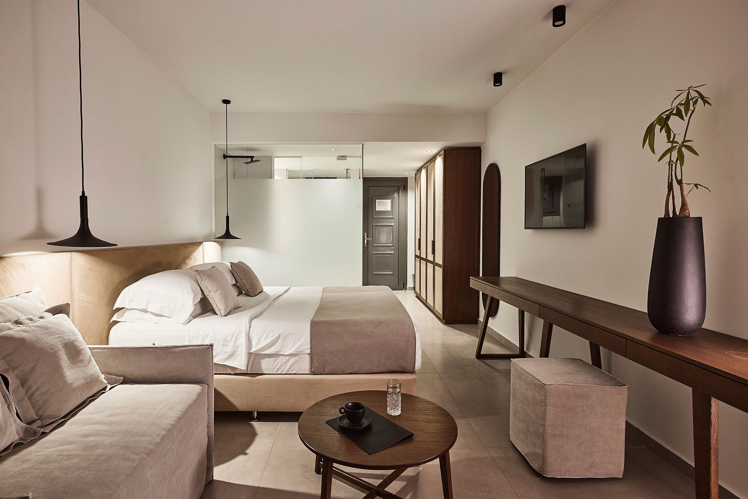 Moderni hotellihuone, jossa parivuode, sohva ja tyylikäs sisustus. (Tekoälyn luoma teksti)