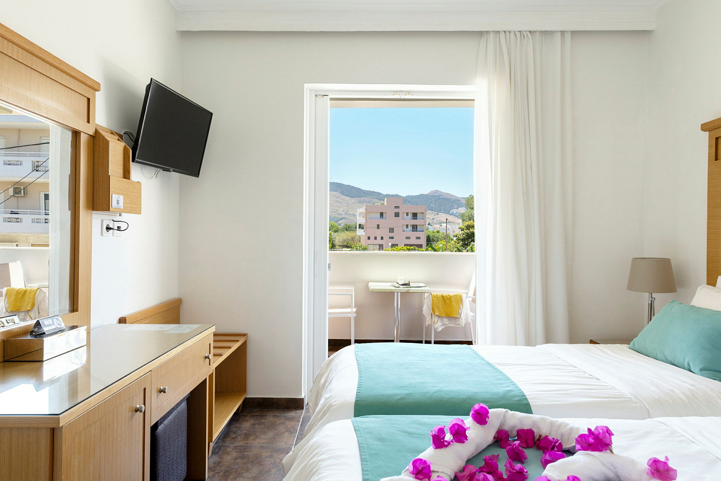 Hotellihuone, jossa kaksi vuodetta ja parveke. Näkymä ympäröiville rakennuksille ja vuorille. (Tekoälyn luoma teksti)