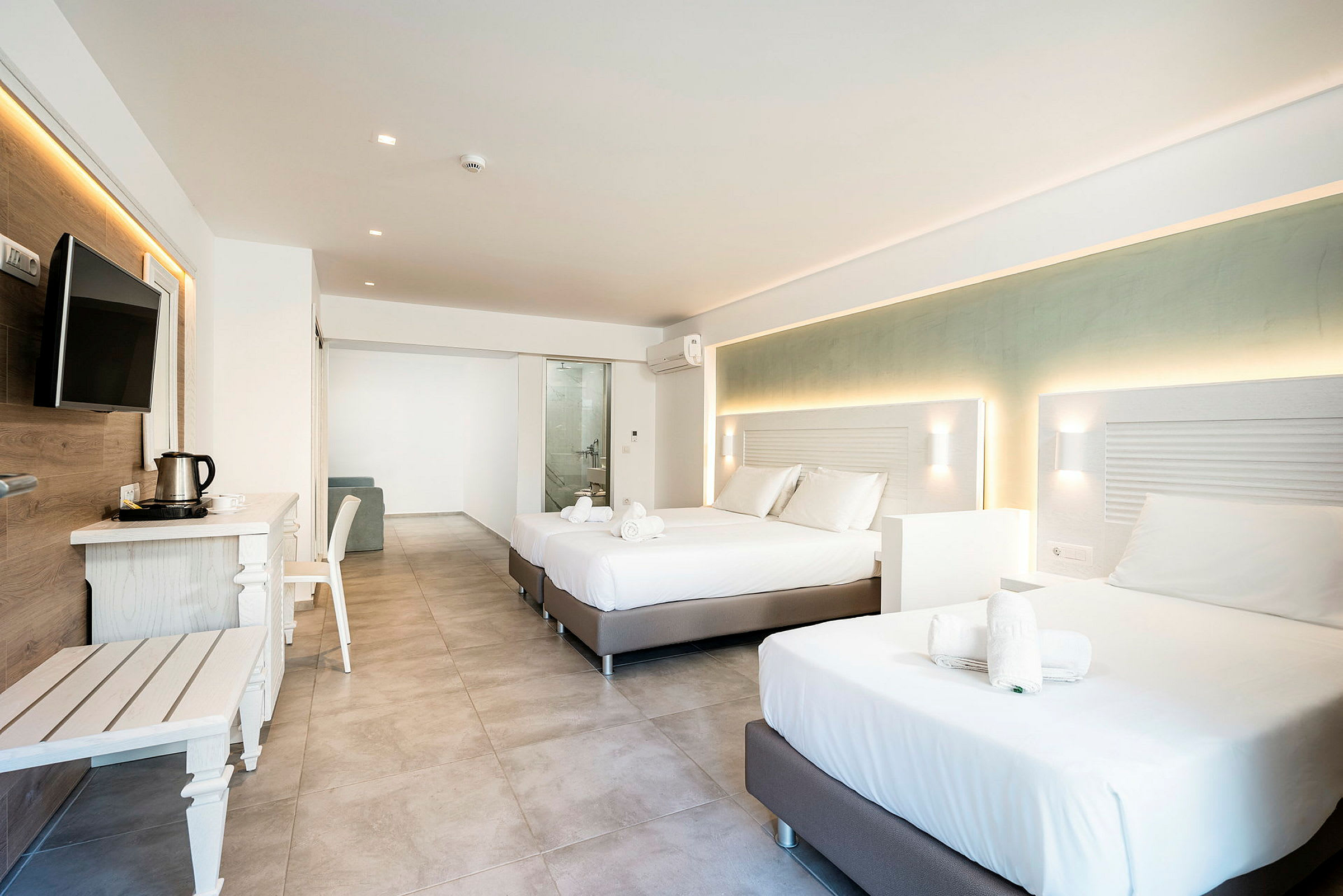 Moderni hotellihuone, jossa on kaksi parivuodetta, huonekaluja ja näkymä kylpyhuoneeseen. (Tekoälyn luoma teksti)
