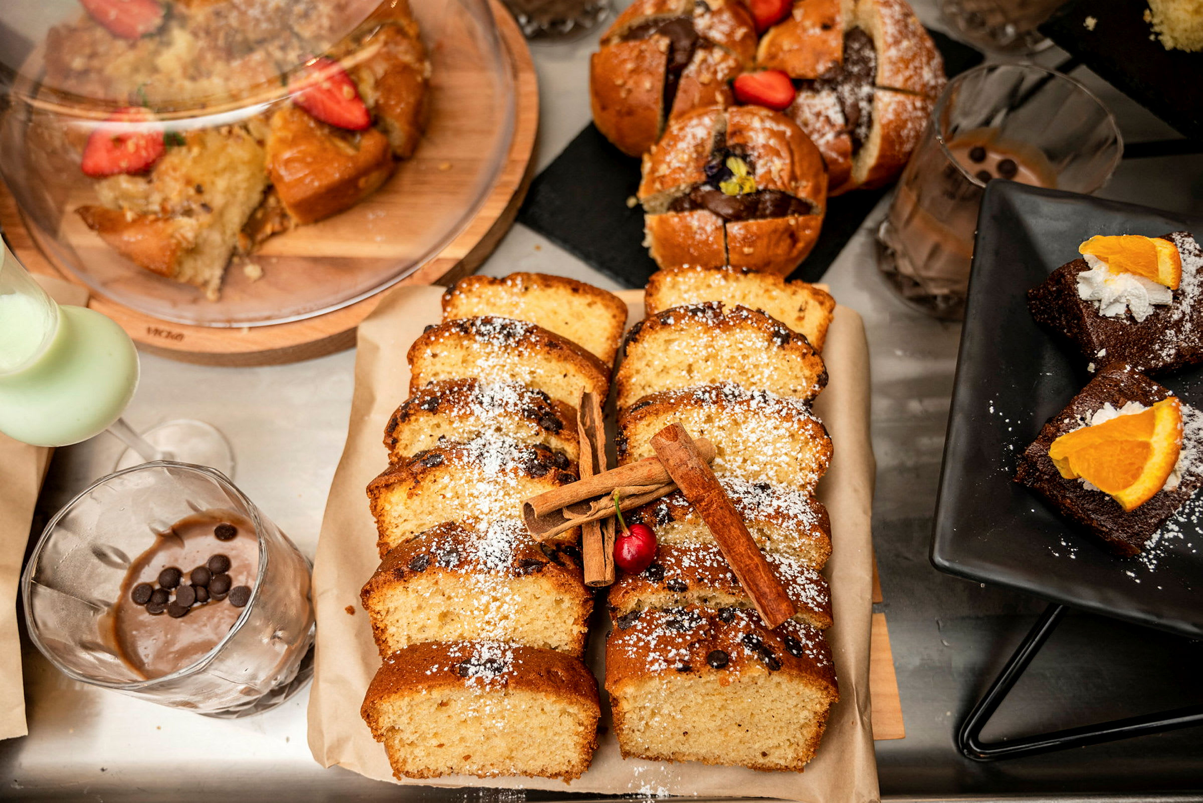 Erilaisia leivonnaisia, mukaan lukien viipaloituja kakkuja, muffinsseja ja suklaaleivoksia koristeilla. (Tekoälyn luoma teksti)