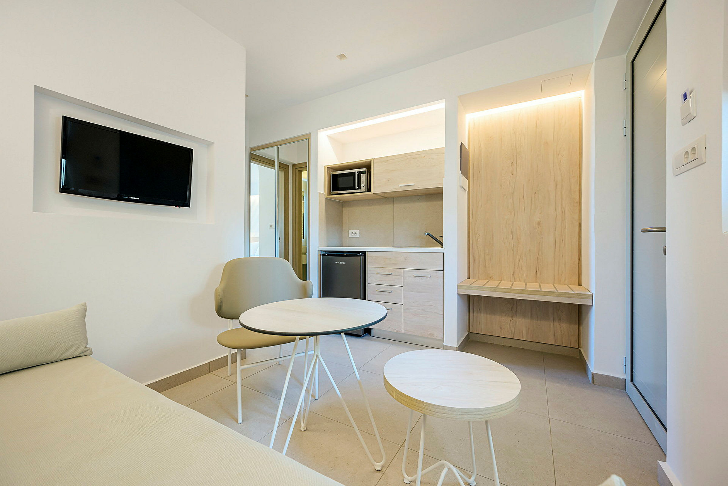 Moderni hotellihuone, jossa pieni oleskelutila ja keittokomero. (Tekoälyn luoma teksti)