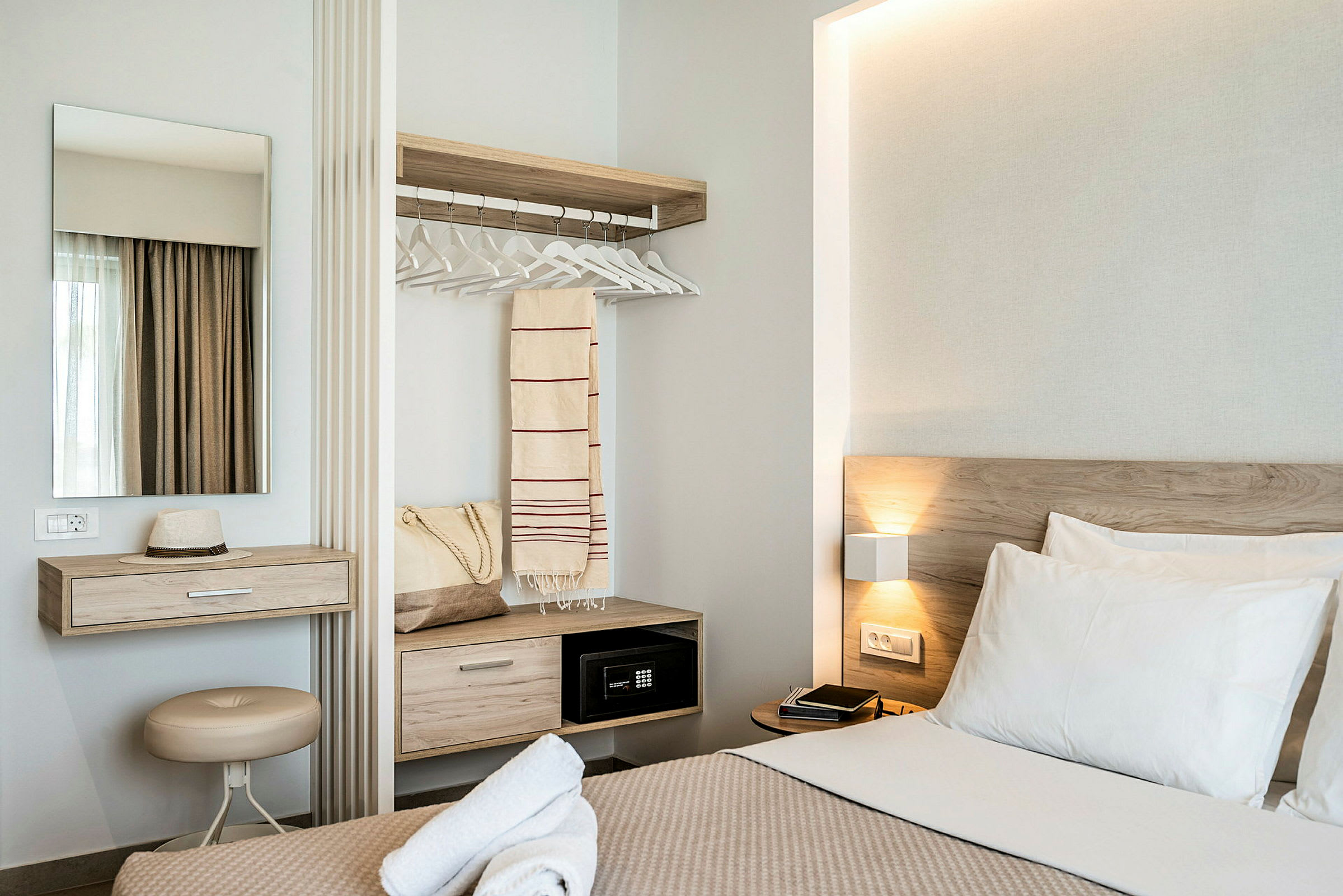 Moderni hotellihuone, jossa sänky, kirjoituspöytä, peili ja vaatekaappi. (Tekoälyn luoma teksti)