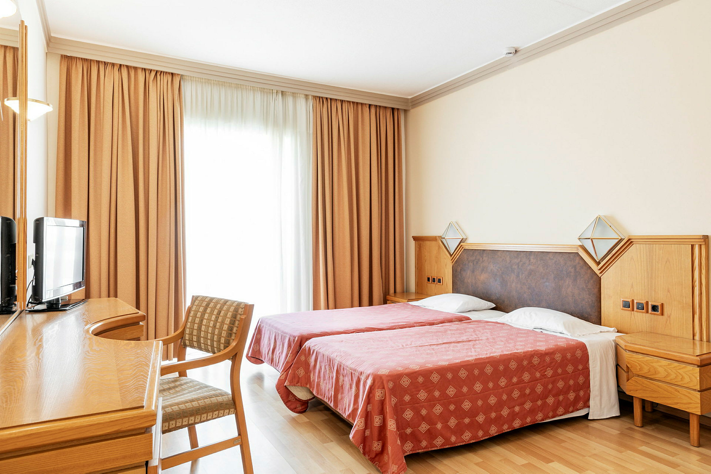 Hotellihuoneessa on kaksi yhden hengen vuodetta, kirjoituspöytä, tuoli ja televisio. (Tekoälyn luoma teksti)
